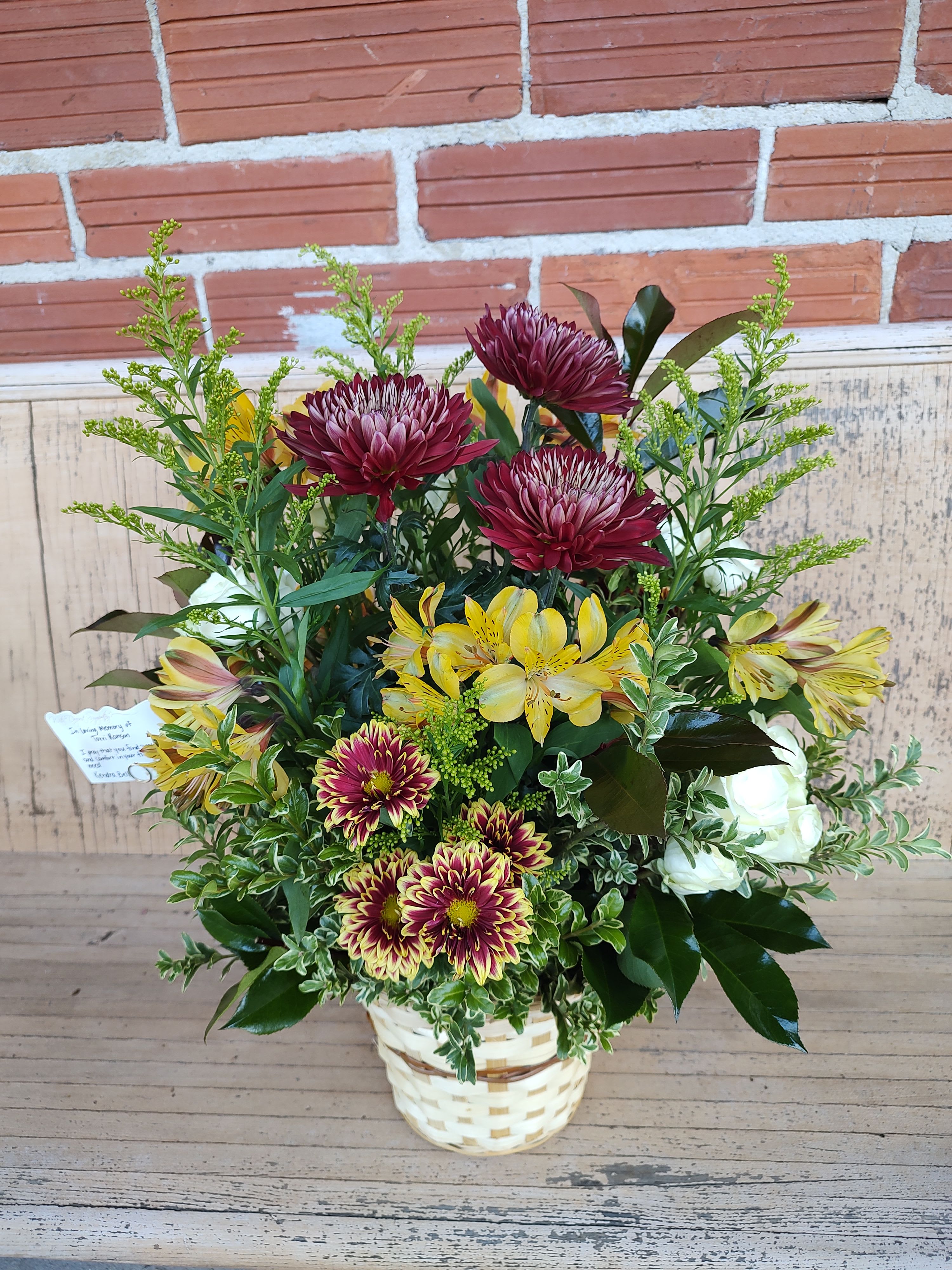 Warm Reflections Basket  - *Please know flowers may vary due to availability***A comforting basket of rich burgundy mums, golden alstroemeria, and lush greenery — designed to offer warmth and peace during times of remembrance. Handcrafted with care in a woven basket, this arrangement brings natural beauty and heartfelt comfort to any memorial or celebration of life.