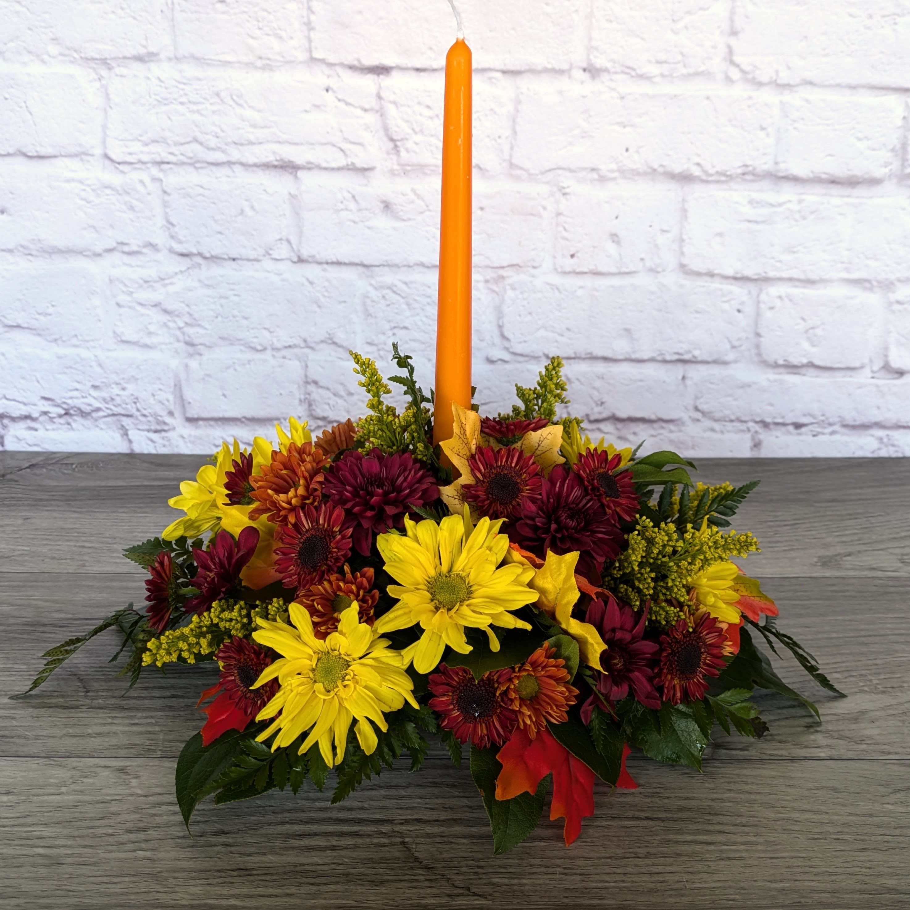 Full of Thanks Centerpiece Full of Thanks Centerpiece - Full of Thanks Centerpiece is A Ladybug Floral exclusive bouquet. Filled with an assortment of fall mums (exact colors and varieties will vary) and topped with an orange candle. Send your thanks to the ones you're thankful for this year with this simple but meaningful centerpiece.  All Around Orientation 6"H without candle 14" with candle X 14"W