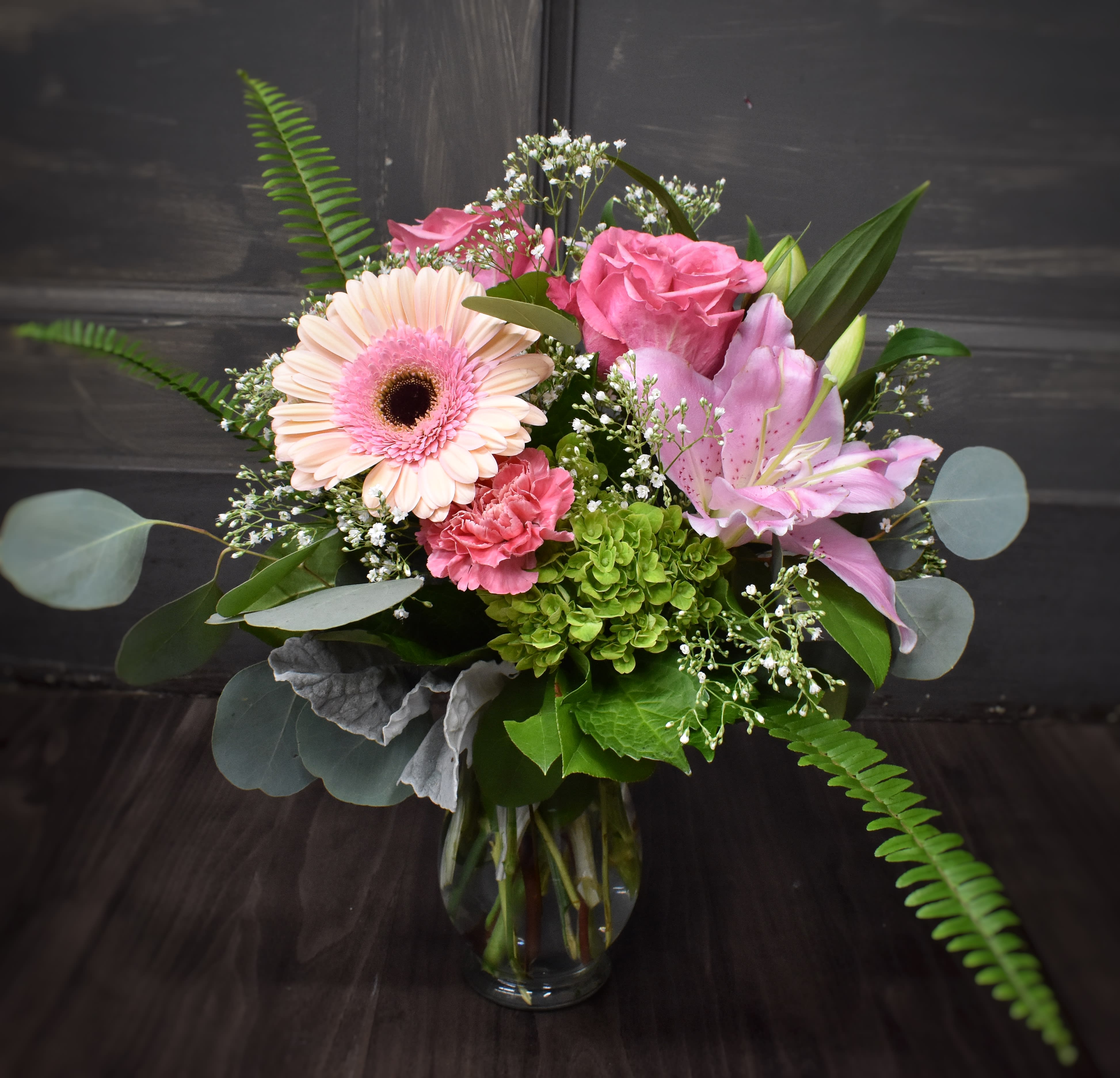 Courage Courage - A pretty pink bouquet designed in a clear vase using lilies, Gerbera daisy, roses and carnations.