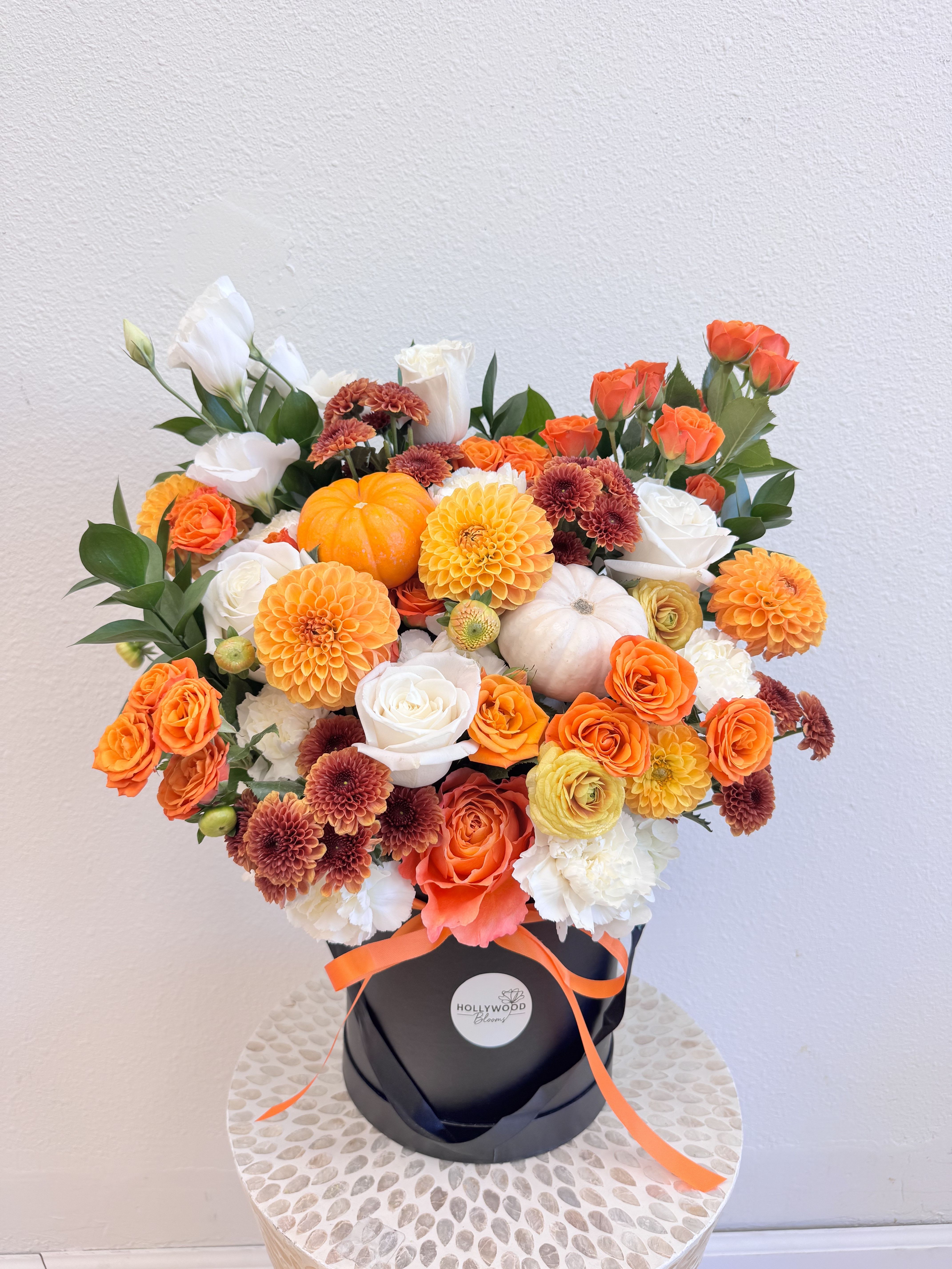 Luxury Fall Flowers in a Box - Celebrate the beauty of the season with our Golden Harvest Pumpkin Box – a luxury fall flower arrangement crafted to capture the warm glow of autumn. This unique design features orange and white roses, dahlias, chrysanthemums, lisianthus, real mini pumpkins, and seasonal greenery — all arranged in an elegant black box. Perfect as a Thanksgiving centerpiece, fall gift, or stylish home decor, this bouquet brings together rich autumn colors, soft textures, and the signature Hollywood Blooms style. Each arrangement is handcrafted by local florists in Los Angeles to add warmth and elegance to any space. Looking for fall flower delivery in Los Angeles or a creative twist on the classic pumpkin flower box? We offer same day delivery in Hollywood, West Hollywood, Beverly Hills, and nearby areas. Pair it with our Autumn Bouquet to complete your seasonal celebration. https://hollywoodblooms.com/los-angeles-hollywood-blooms/fall-pumpkin-arrangemen.html