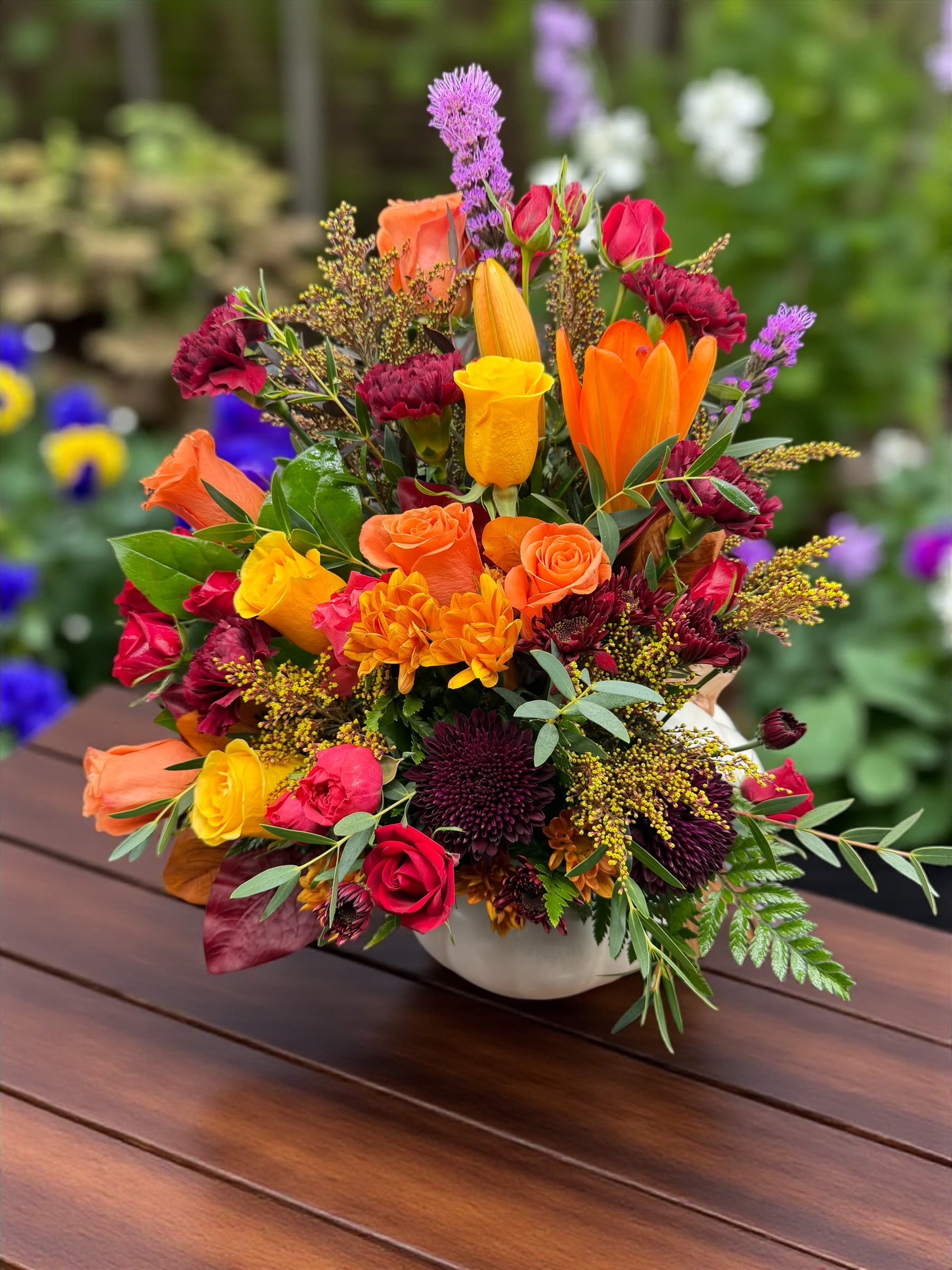 Pumpkin  - A breathtaking autumn-inspired floral arrangement bursting with rich seasonal colors! Featuring vibrant orange lilies, golden roses, burgundy mums, red spray roses, and touches of purple liatris, this design captures the warmth and beauty of fall. Perfect for any celebration or to brighten someone’s day with elegance and color. 