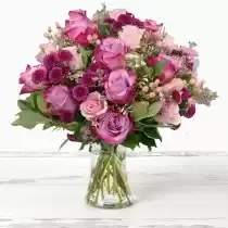 Blushing Beauty Vase - A breathtaking arrangement of pink and lilac roses, accented with sugar-flair hypericum berries, purple santini chrysanthemums, and elegant touches of rose gold fern.  Each bloom is artfully arranged in a clear glass vase and finished with Luxiviani’s signature black satin ribbon, creating a look that’s effortlessly luxurious and full of charm.  Designed to bring soft romance and timeless beauty to any space — perfect for birthdays, love notes, or simply brightening someone’s day.  