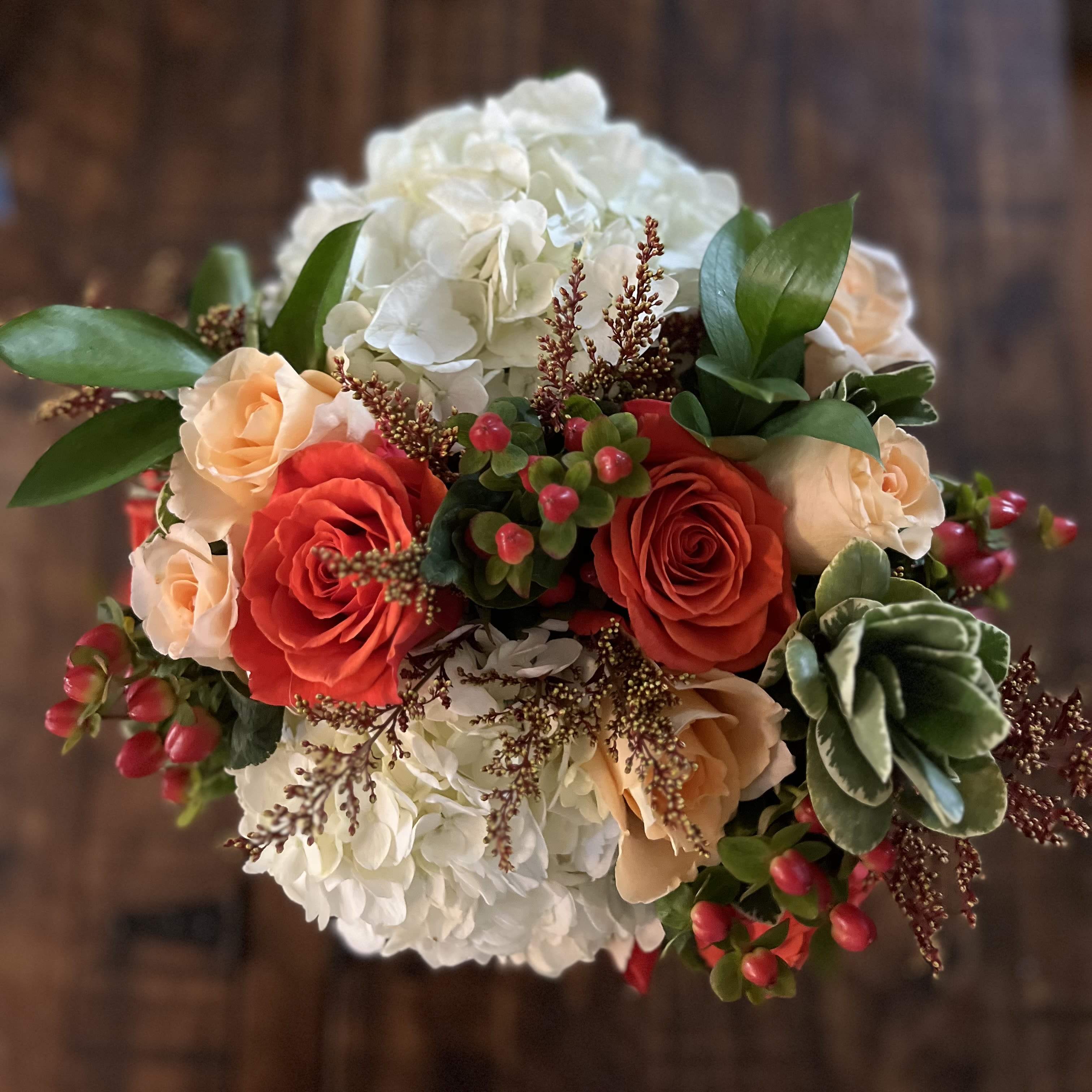 Falling for You  - Autumn-Inspired Elegance - Capture the warmth and richness of the season with our Falling for You arrangement — a striking blend of creamy hydrangeas, vibrant burnt orange and peach roses, and seasonal greenery, accented by red hypericum berries and earthy textures. Artfully arranged in a compact, elegant style, this bouquet radiates cozy sophistication and heartfelt charm.  Perfect for fall weddings, anniversaries, or as a thoughtful “just because” gift, it’s a beautiful way to say I’m thinking of you with every vibrant bloom.