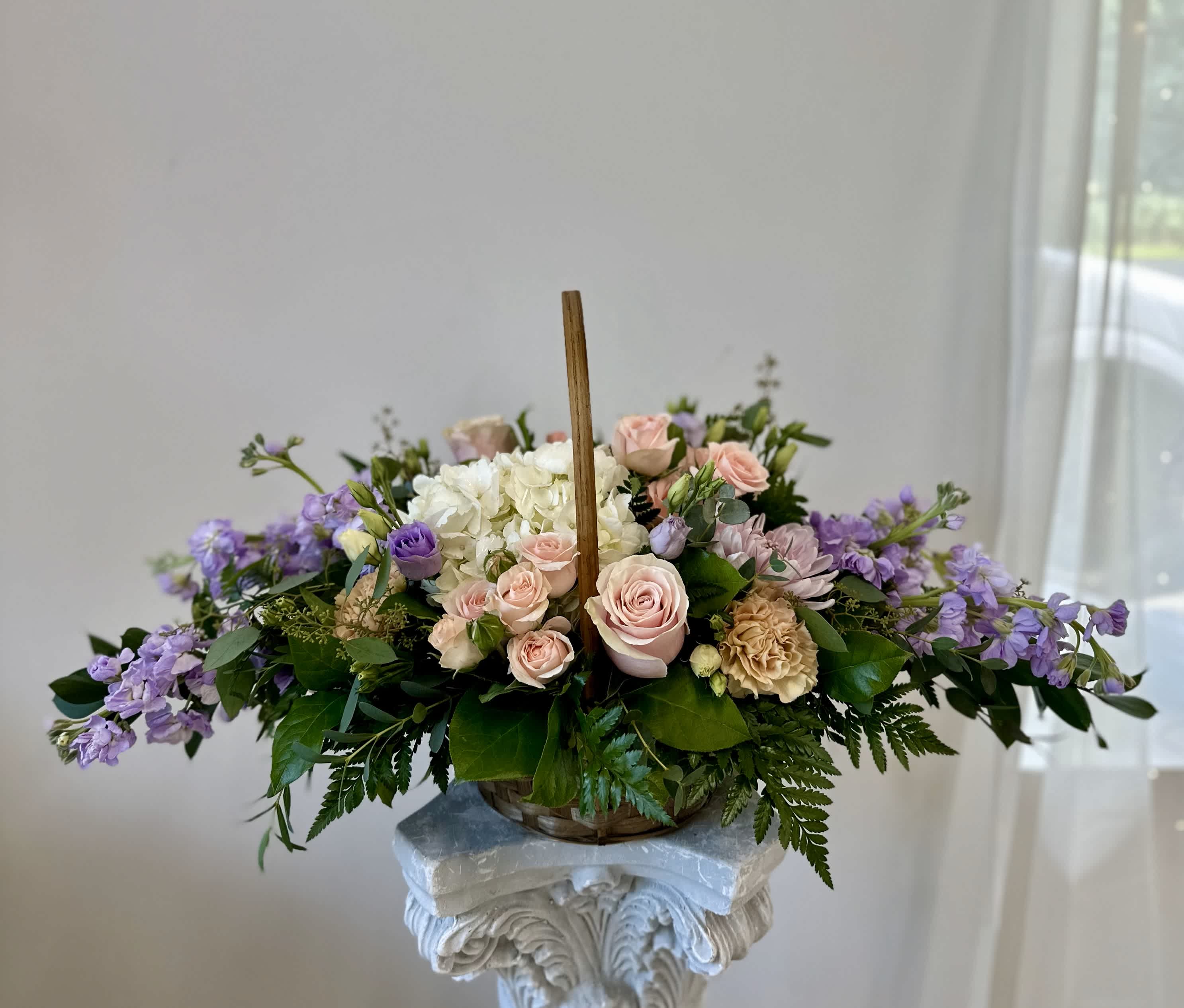 Pastel Peace Basket by Westford Florist Art by Veny - Embrace the essence of serenity with the Pastel Peace All Around Basket from Westford Florist Art by Veny. Suitable for home sympathy sending, church and funeral home. Designed with elegance in mind, this sympathy arrangement features a harmonious blend of white hydrangeas, blush and light pink roses, delicate lavender lisianthus, fragrant stock, and disbud mums—all framed by lush greenery. The long and low style adds sophistication to any space while conveying heartfelt condolences. Perfect for honoring cherished memories or offering comfort during difficult times, this pastel-toned masterpiece is a thoughtful gesture that speaks volumes without saying a word. The Pastel Peace Basket by Westford Florist offers a graceful expression of sympathy, perfect for honoring cherished memories.