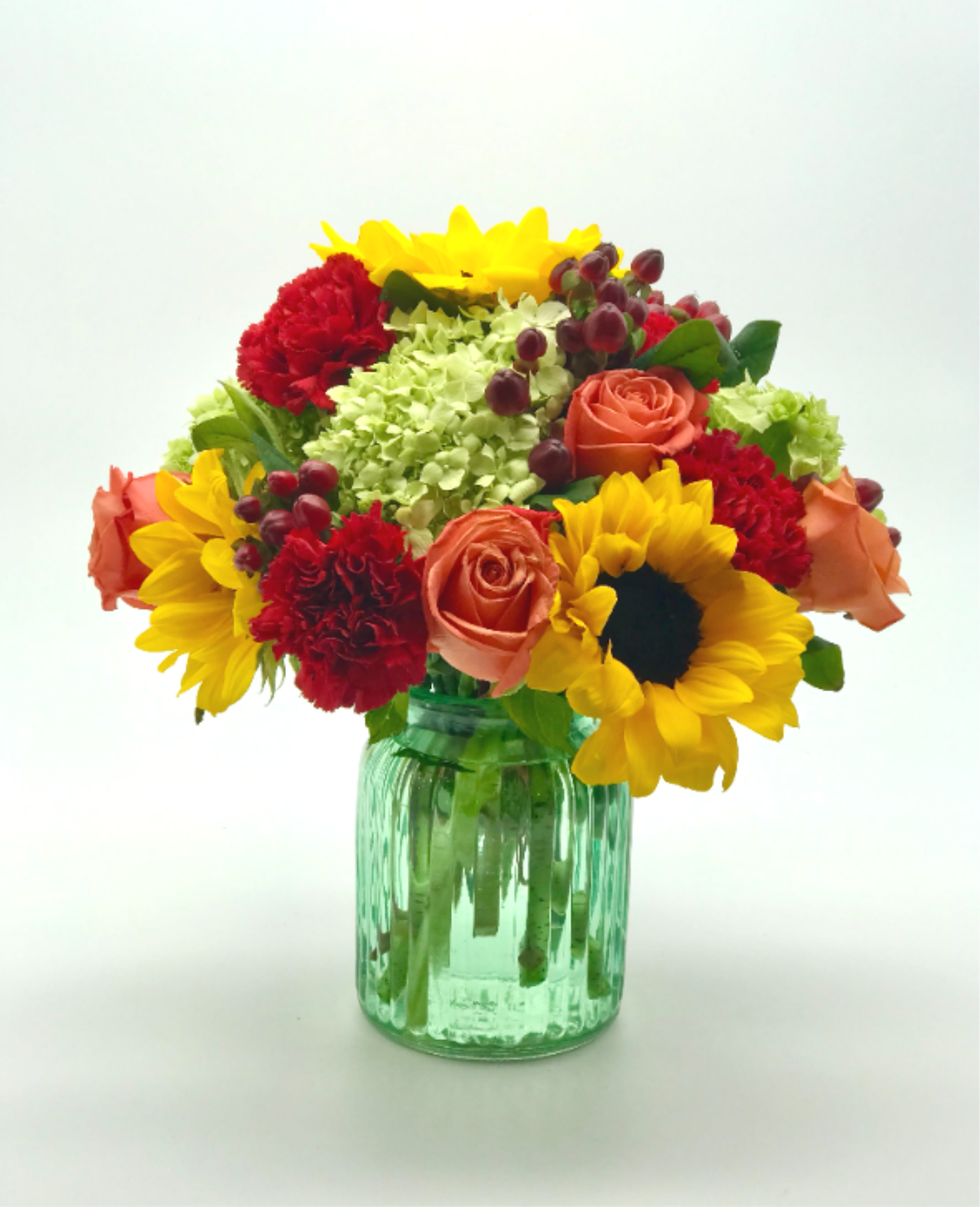 Eternal Summer Bouquet - A Bouquet of Sunflowers with Orange Roses with Red Carnations and Green Hydrangeas in a green glass vase.