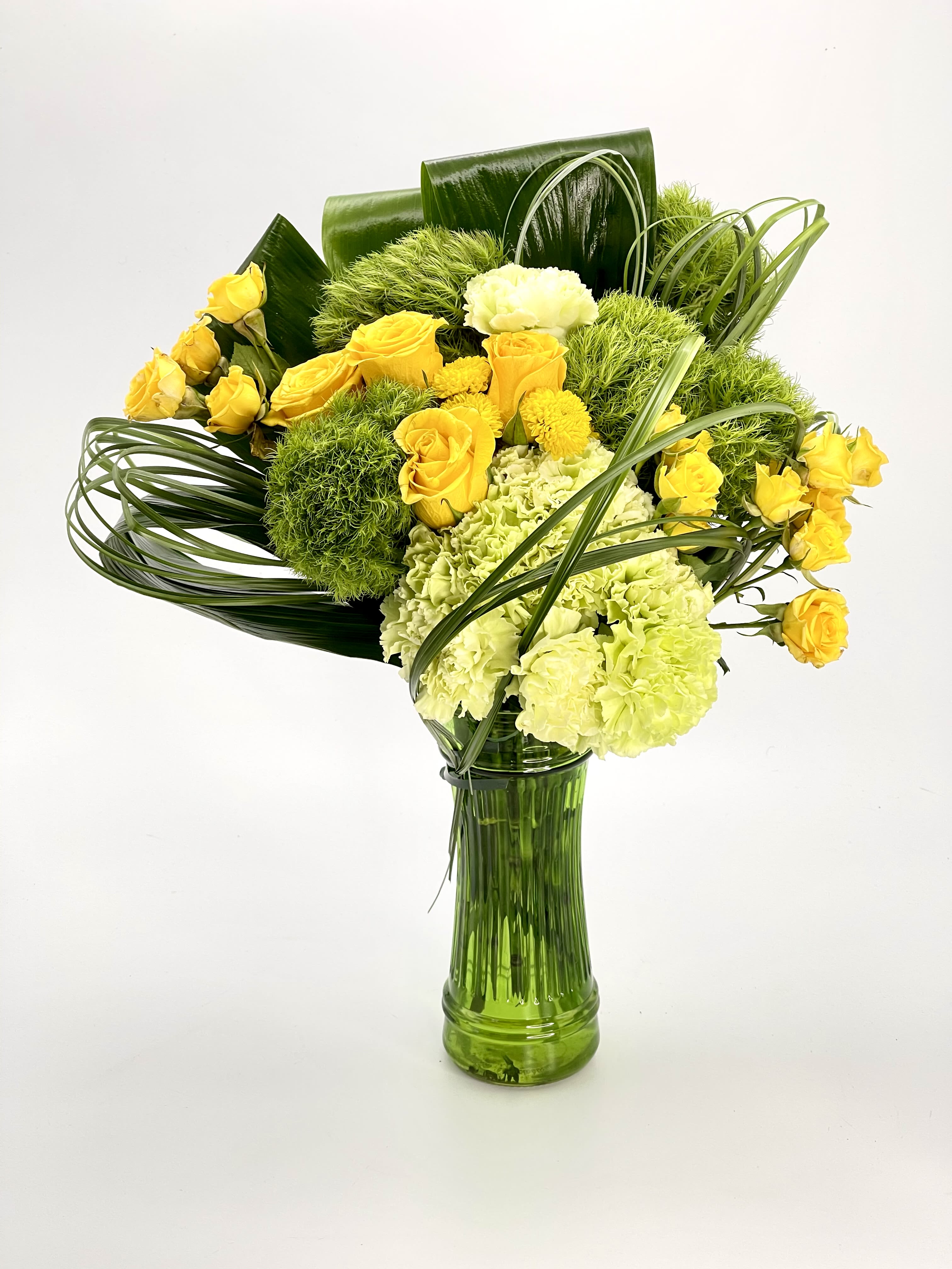 Green Garden - A bouquet of tropical leaves with green Carnations, Green Spider and yellow Roses and yellow spray Roses in a green glass vase.