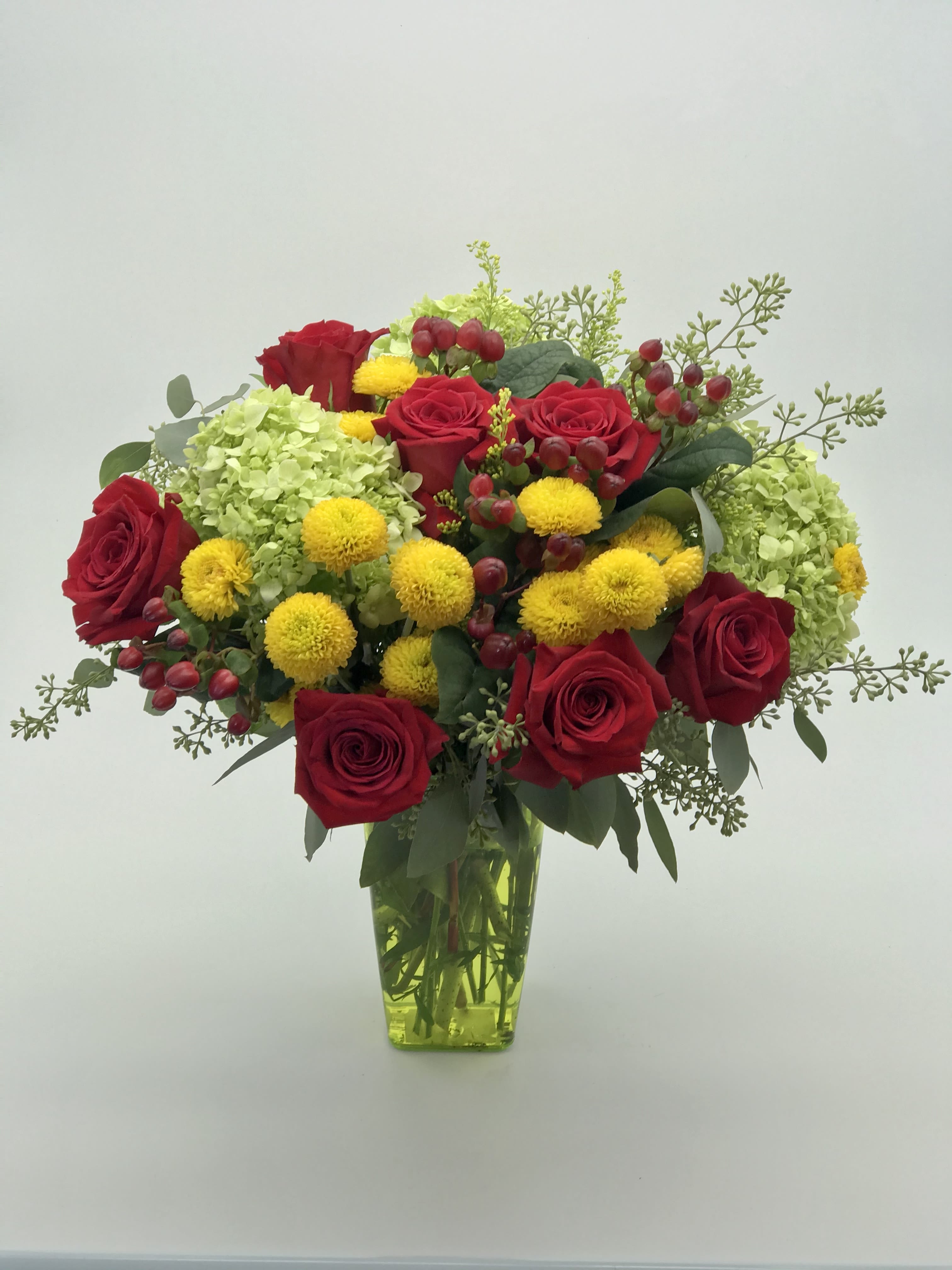 Warm Wishes Bouquet - An Arrangement of Red Roses, Hydrangeas, Yellow button mums, and berries in a acrylic vase.