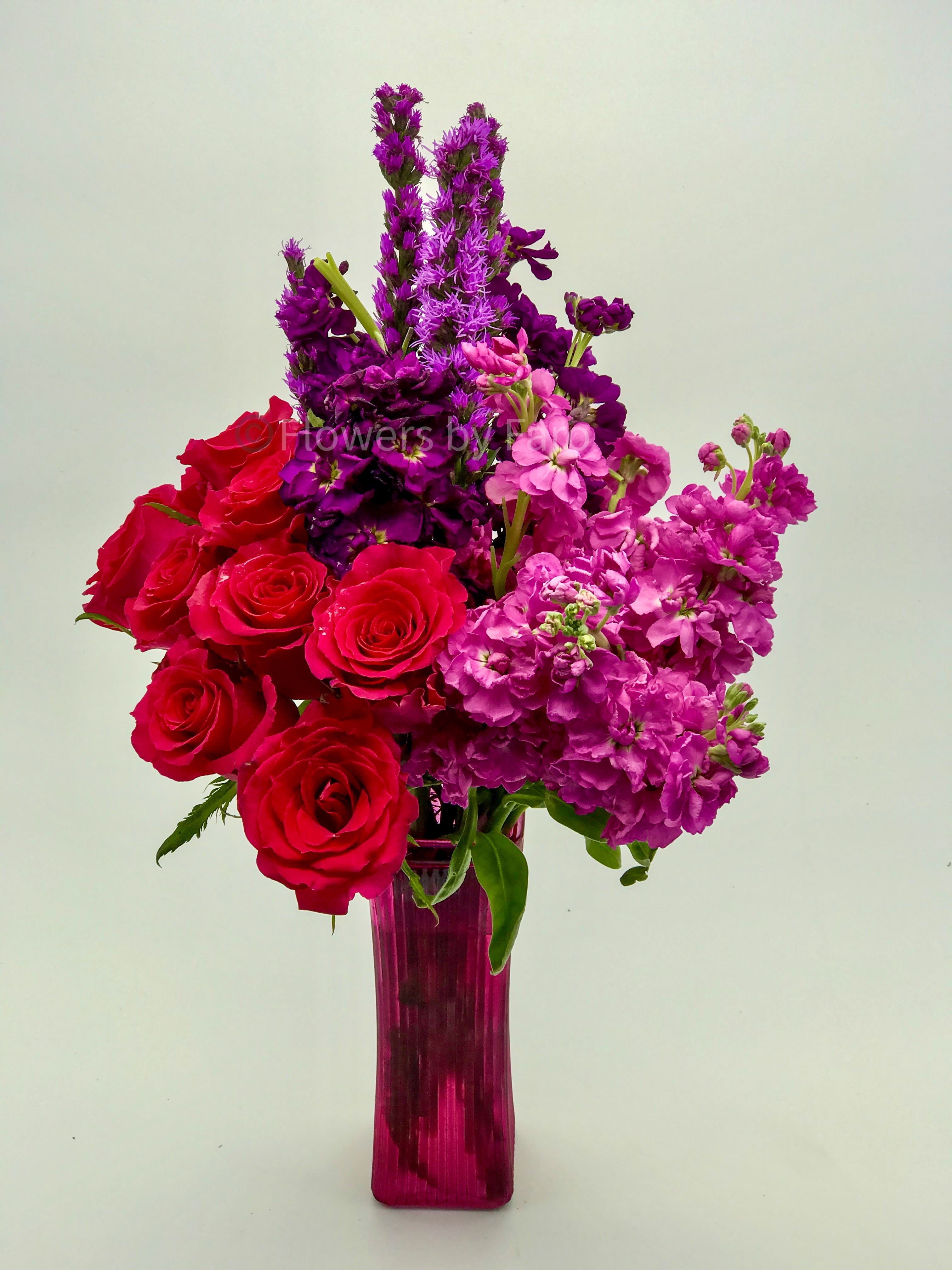 You're Beautiful Bouquet - A lovely bouquet of Red Roses with Purple and Lavender Stock in a red glass vase.