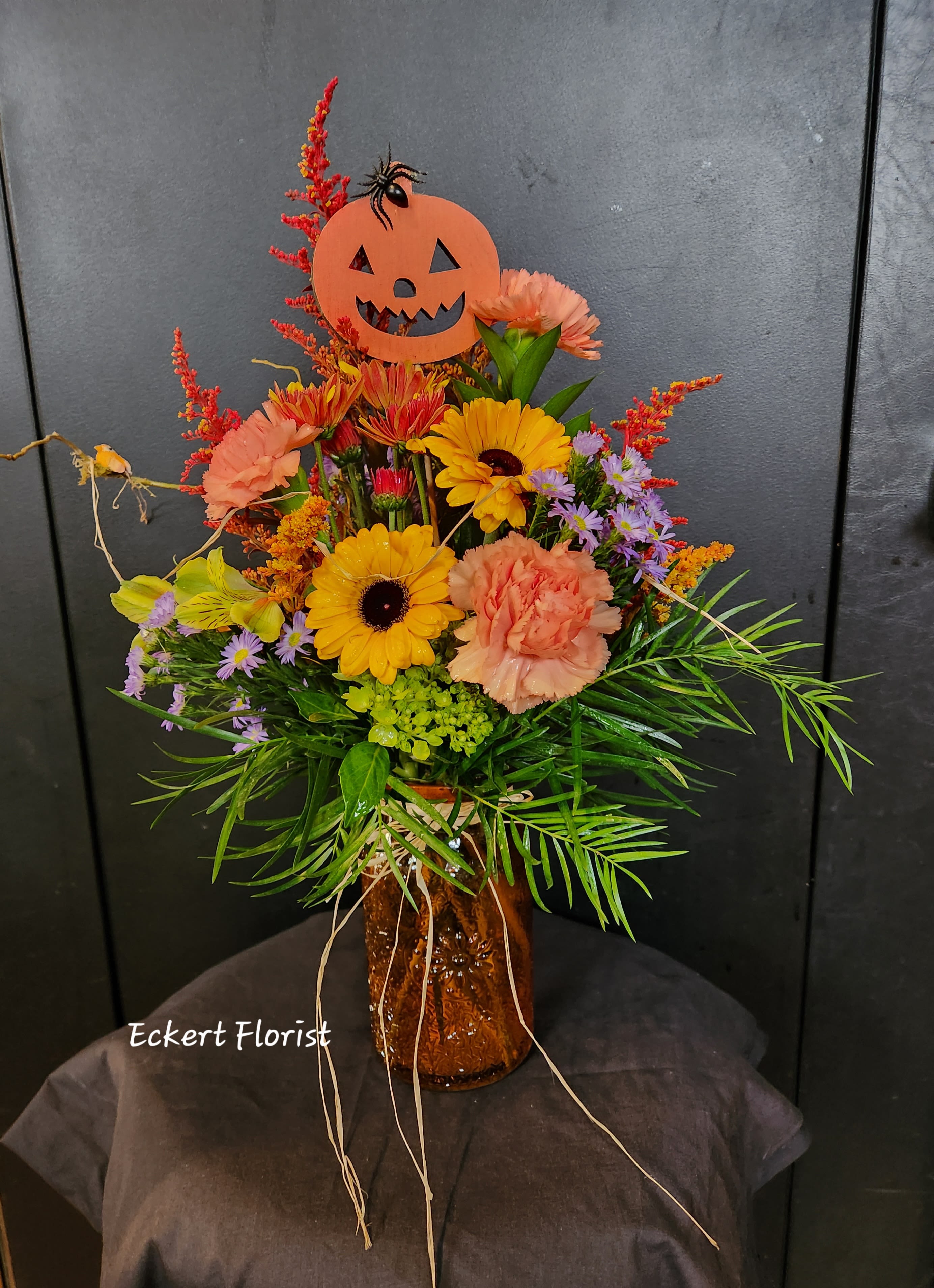 Eckert Florist's Happy Halloween Bouquet *Our Local delivery Only Eckert Florist's Happy Halloween Bouquet *Our Local delivery Only - What a nice surprise to give and/or receive this fresh vase arrangement. Designed with autumn colors, this bouquet includes a cute Jack-O-Lanter pick just in time for Halloween. *Our local delivery only.