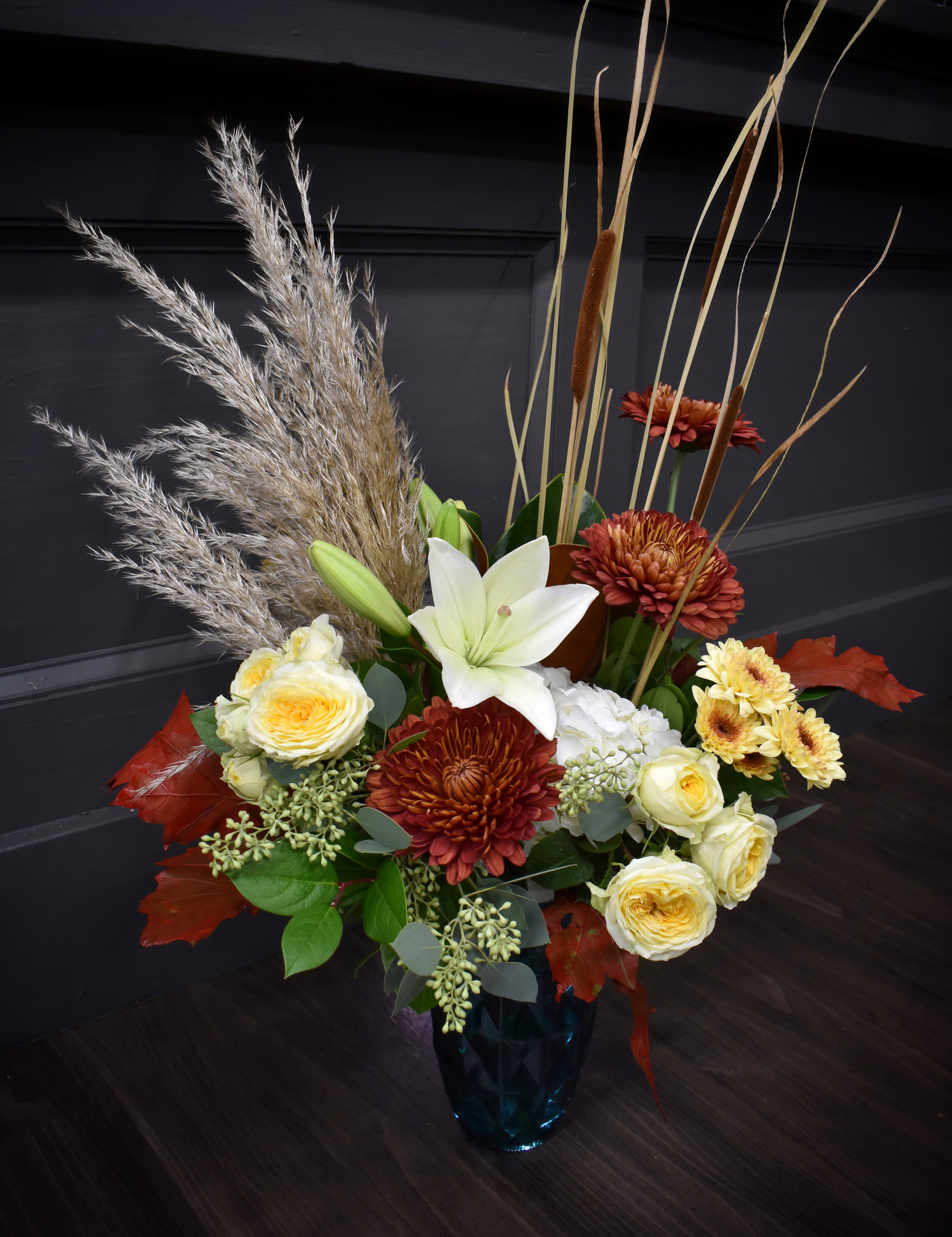 Boho Bound  Boho Bound  - This eclectic mix of movement and textures is an adventure through the seasons. Cattails stand tall above a mix of hydrangea, lilies, mums and spray roses accented with a mix of foliage and a full stem of pampas grass. Upgrade this arrangement to add a luxurious stem of cymbidium orchid blooms.