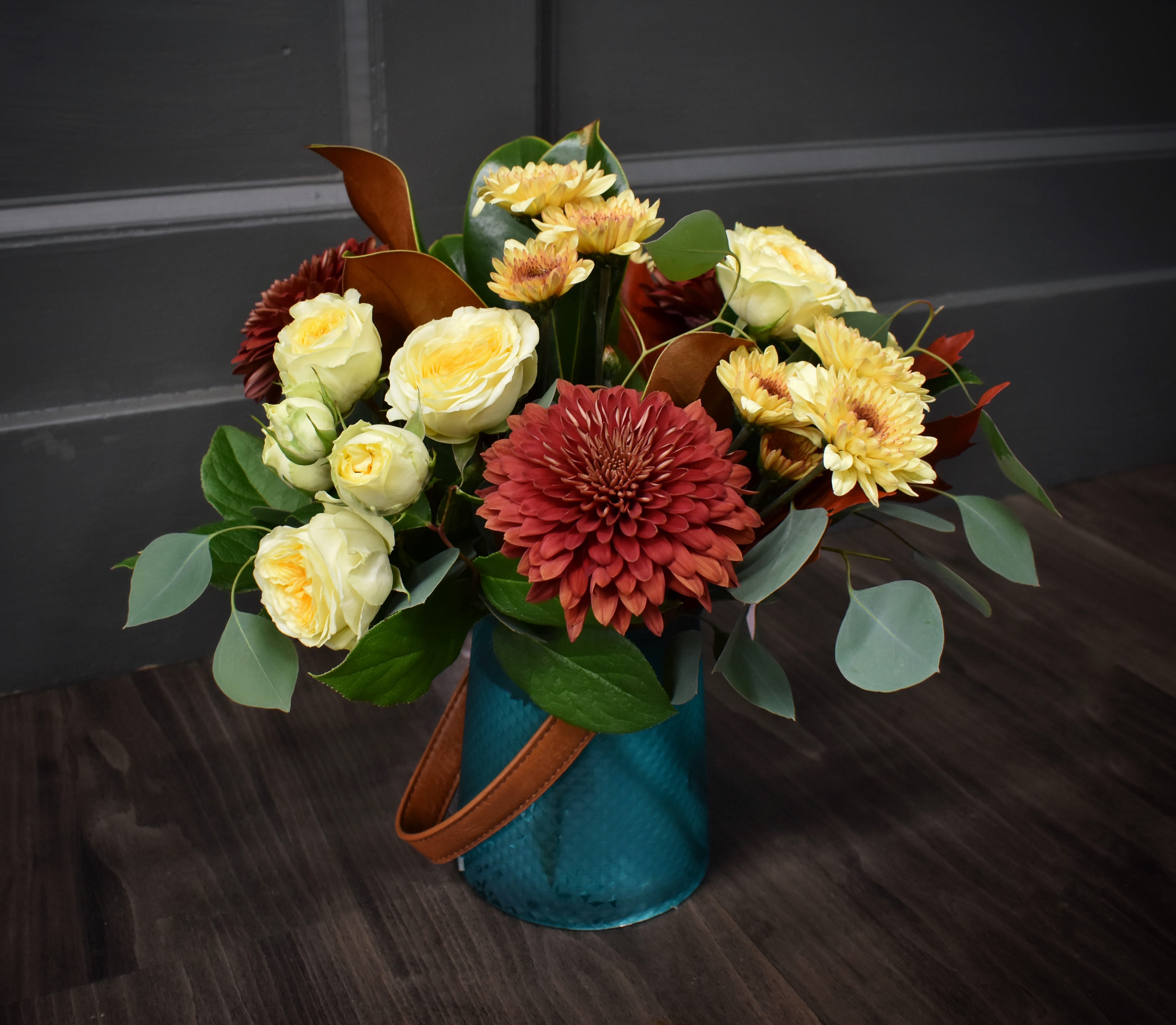 Gypsy Blues  Gypsy Blues  - Featuring a bold mix of sprays roses, mums, poms, magnolia and fall leaves, this jewel-tone blue vase, complete with a leather handle, embodies wanderlust. This vibrant mix of colors evoke a sense of adventure, right here at home.