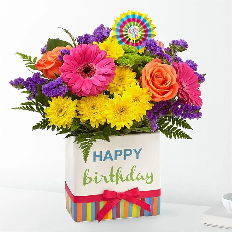 Birthday Brights Bouquet - The Birthday Brights Bouquet is a true celebration of color and life to surprise and delight your special recipient on their big day!  Presented in a modern rectangular ceramic vase with colorful striping at the bottom, &quot;Happy Birthday&quot; lettering at the top, and a bright pink bow at the center, this unforgettable fresh flower arrangement is then accented with a striped happy birthday pick to create a fun and festive gift.
