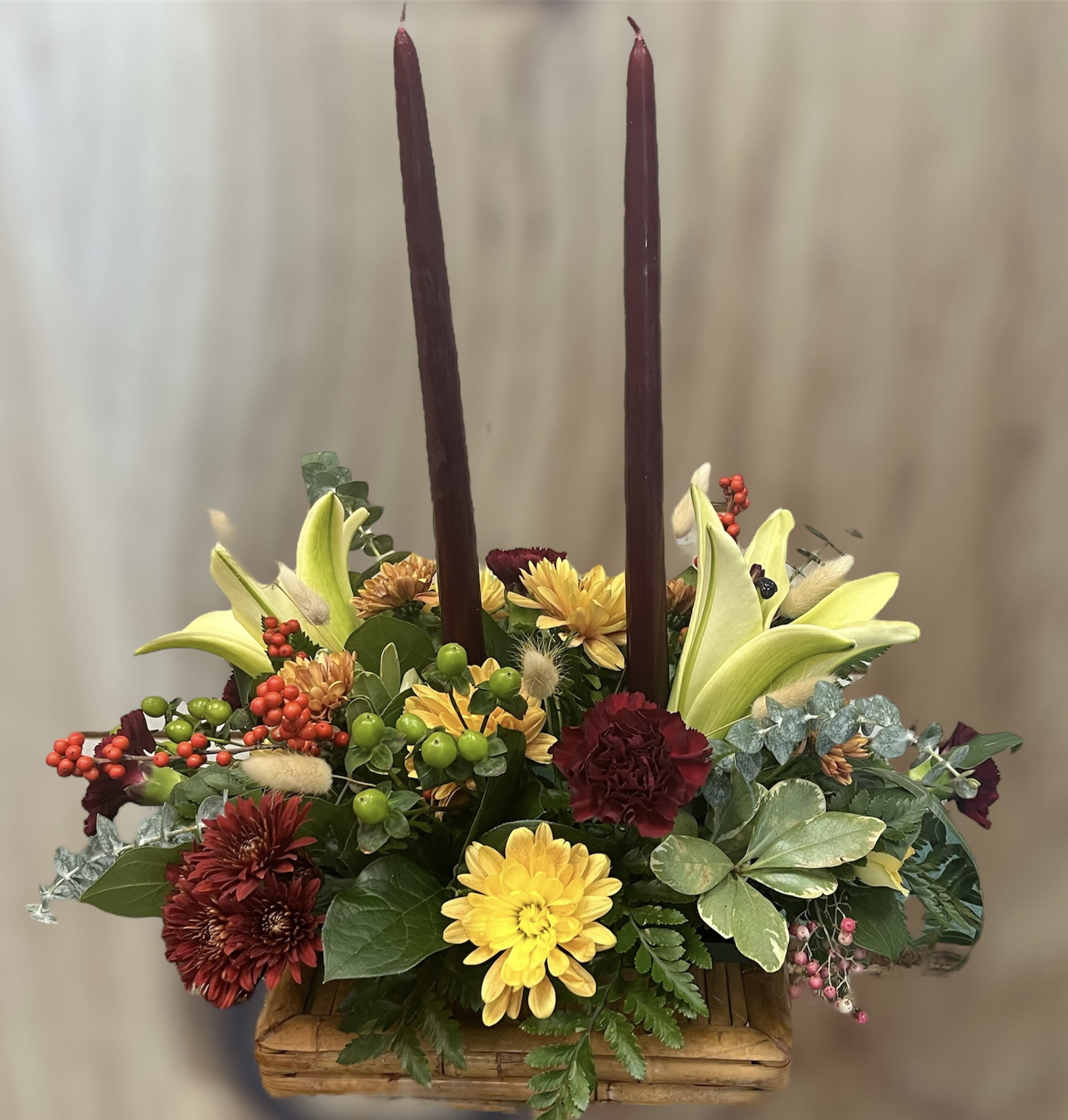 Family Gathering Centerpiece - Graciously gather your family around the warm glow and classic autumn colors of this stunning Thanksgiving centerpiece. A lush variety of burnt orange blooms are gathered under a pair of tall, graceful candles - perfect for decorating your Thanksgiving dinner table, entryway or hearth.