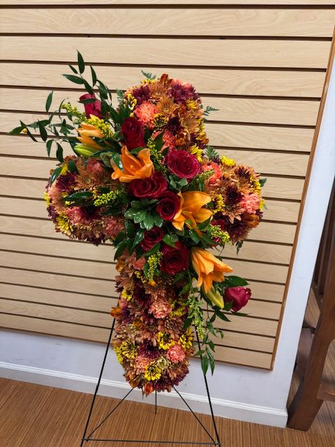 Fall Cross on Stand Fall Cross on Stand - Mixed fall cut flowers - red roses, orange carnations, brown cushions, gold cushions, and orange alstromeria - Standing Cross