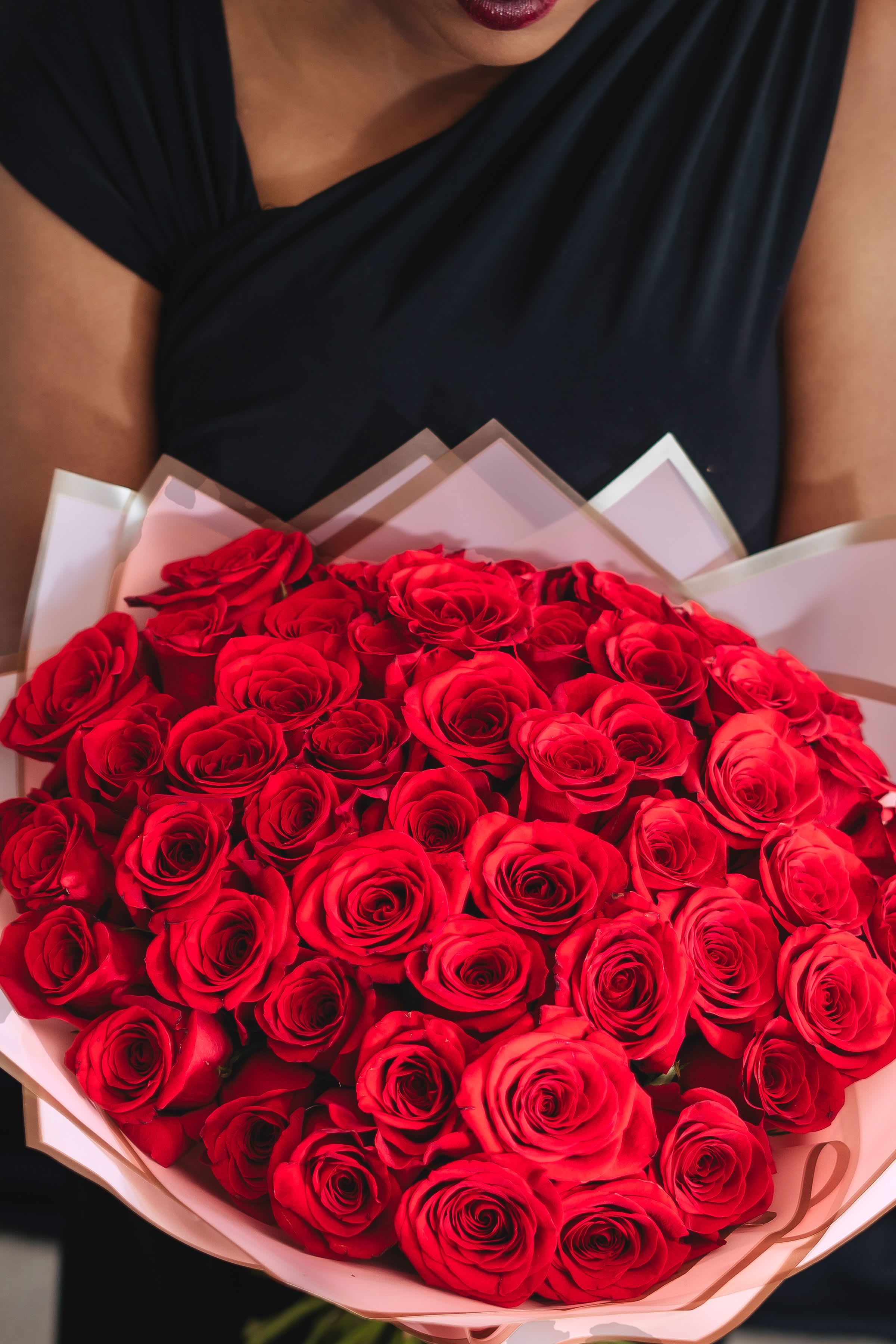 Radiant Red Rose Bouquets - A beautiful round hand bouquet of 48 fresh red roses, expertly arranged for an elegant touch to any occasion.  Please note: The bouquet shown is a 48 -hand bouquet with pink wrap. Whilst we make every effort to source the exact ingredients, occasionally it may be necessary for our florists to substitute with a similar stem.