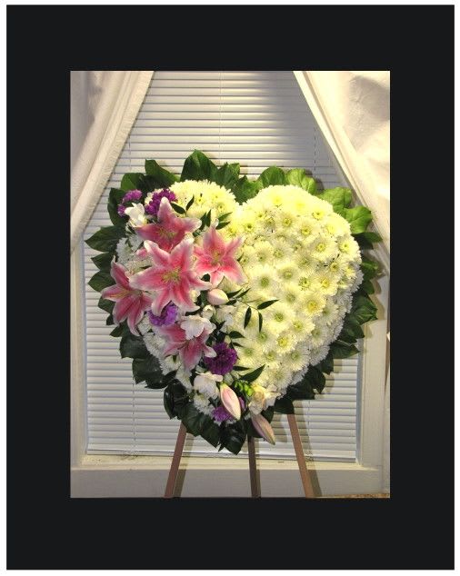 Heart Felt Sentiments Heart Felt Sentiments - Share your Heart with someone that you loved with this Heart shaped memories piece, we use White Cushion Pompom stems with pink oriental lilies and purple carnations; surrounded with salal stems it comes on a 48" Wire Easel.  Approx 22" x 22"