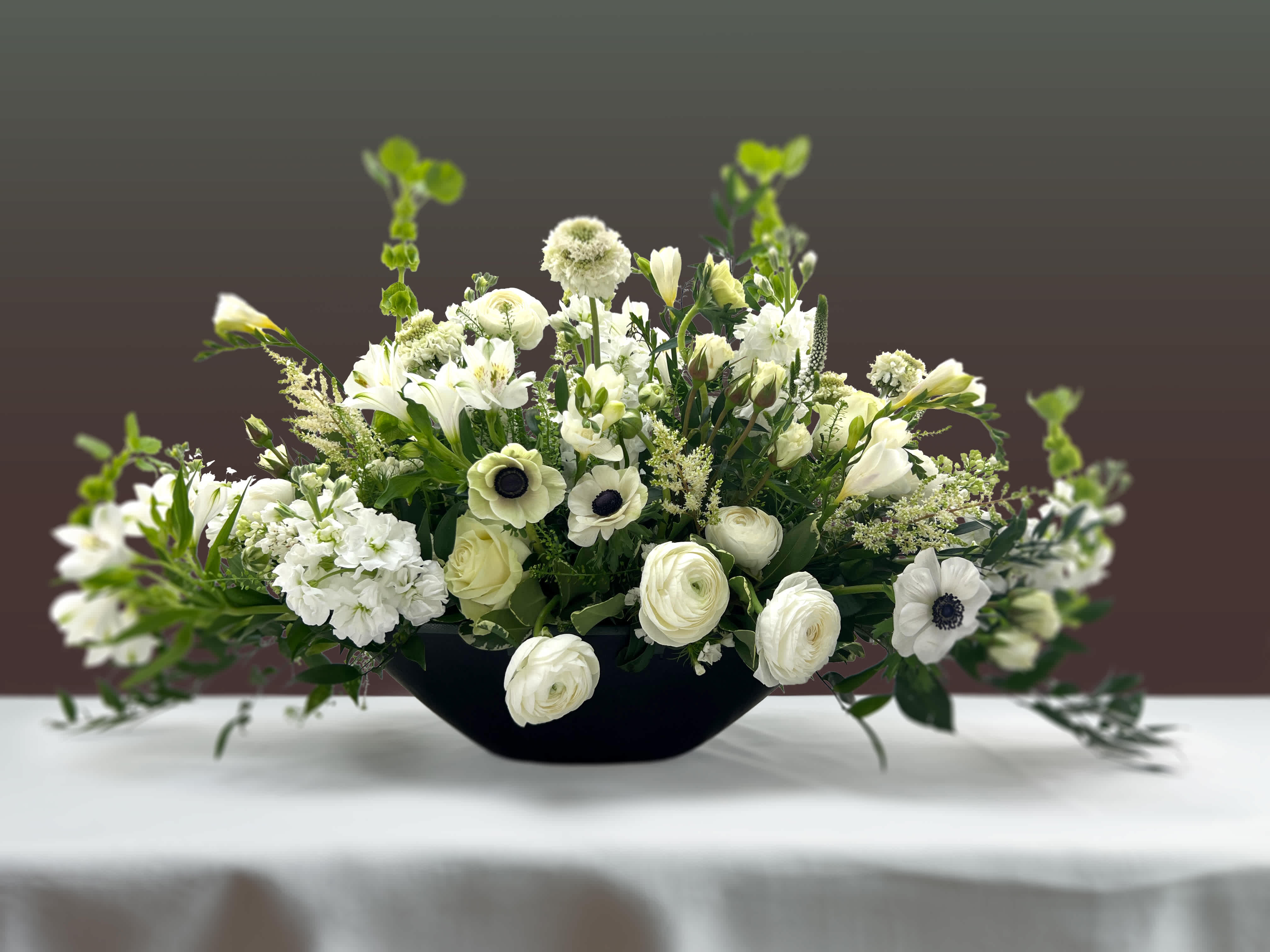 Centerpiece | Libertas  - An eye-catching centerpiece of panda anemone, scabious, astilbe, freesia, ranunculus, stock, roses, and veronica.