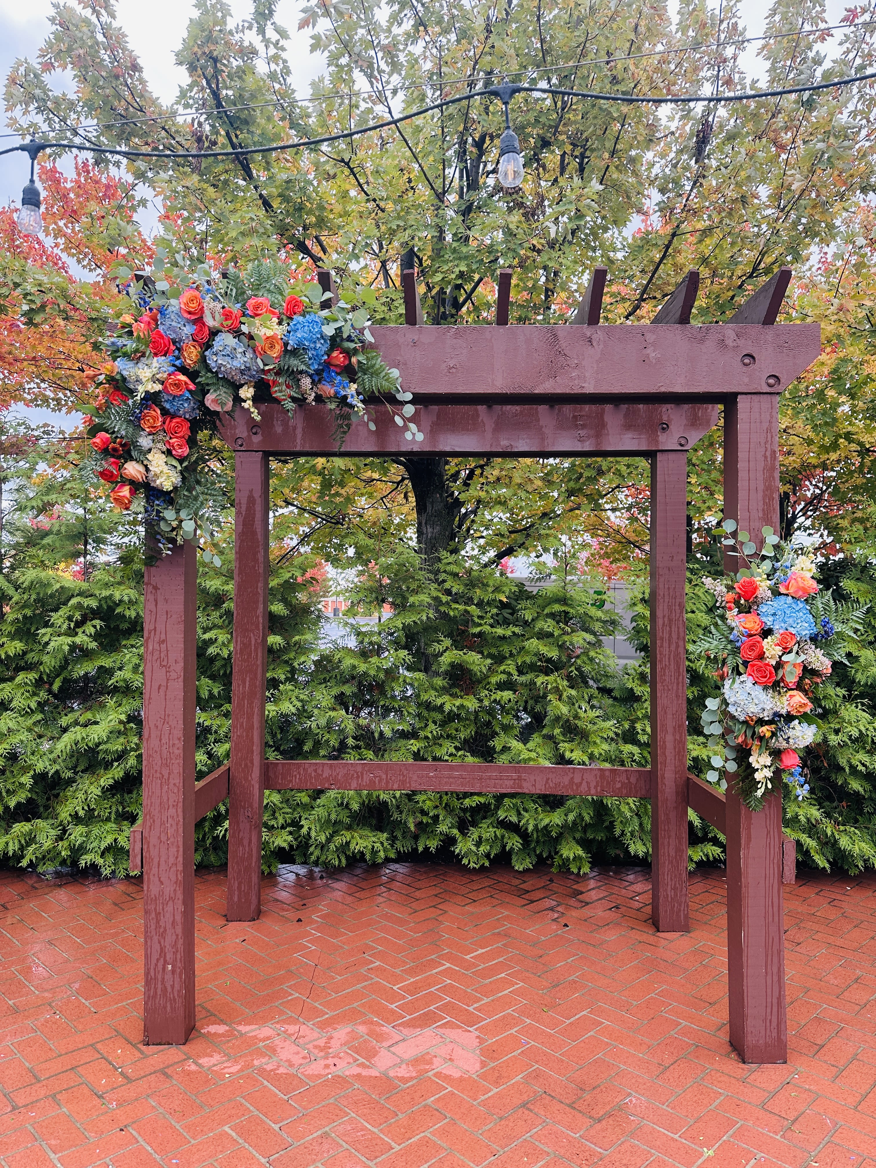 Ryllie wedding arch - Beautiful two asymmetrical swags arch decor with bright fall bohemian colors of orange blue and white with roses, hydrangea and other colors  