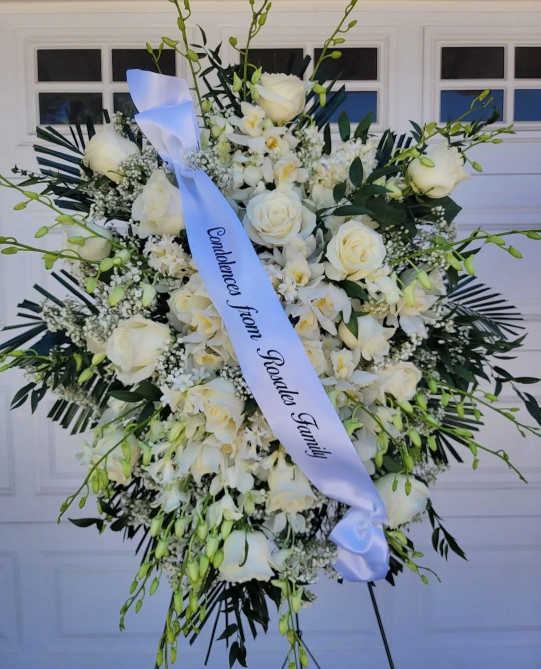 White Orchid Sympathy Standing Spray - An all white premium orchid tribute, this funeral spray is pure and tranquil. Featuring a variety of white flowers and green palms this elegant funeral spray brings a feeling of peace to it's surroundings.