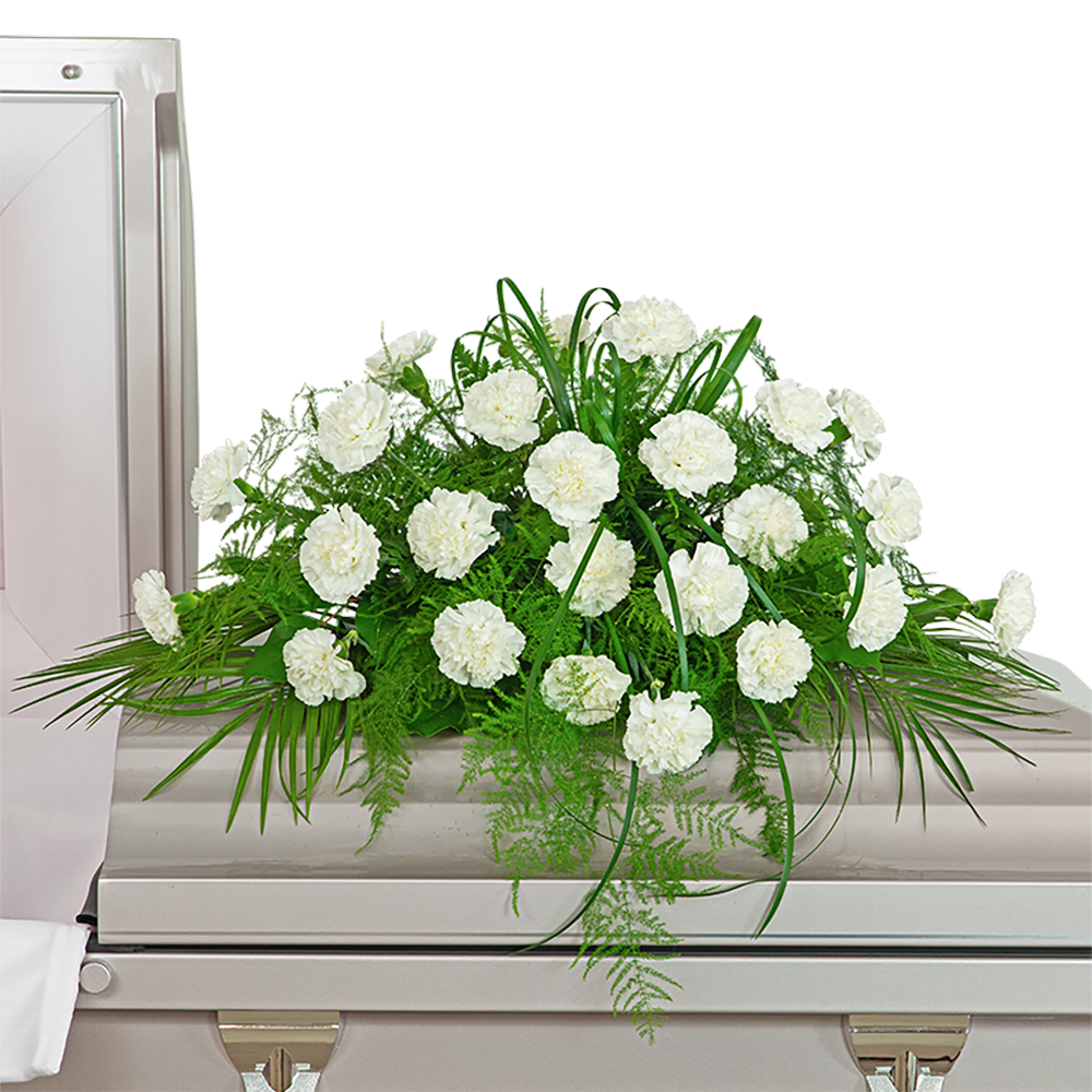 White Divinity Casket Spray - The White Divinity Casket Spray is a classic design that can be easily customized to your color preference. Carnations are a popular choice for funeral flowers and can carry different symbolic meanings, depending on the color you choose. White carnations convey pure love and innocence, red carnations symbolize admiration, and pink carnations stand for remembrance. The Divinity Casket Spray features Carnations, Robellini, Plumosa, Lily Grass, and other premium foliage. The casket flowers are typically provided by the family of the deceased as a heartfelt memorial from the family and are designed to sit on the lid of the casket for a funeral service or memorial. For any and all family flowers, feel free to contact our shop for ideas and variations to make your final tribute extra unique and special.   The image shows the Deluxe arrangement.