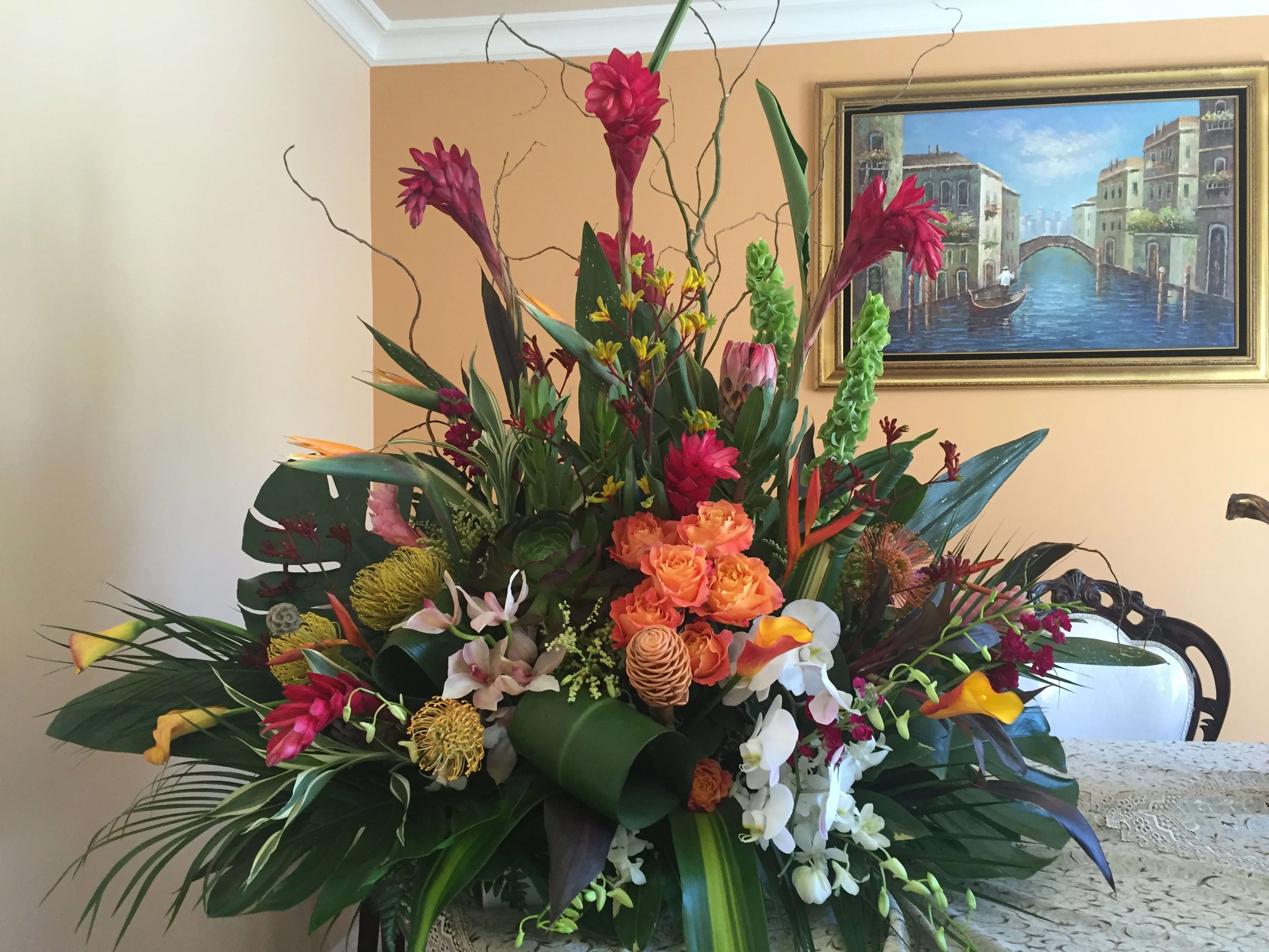 Exotic tropical arrangament 007 Exotic tropical arrangament 007 -  Exotic and beautiful tropical flowers artistically arranged collection of tropical and fresh flowers featuring bright red and pink ginger, yellow pincushion protea, stunning Birds of Paradise, golden beehive ginger, kangaroo paw, large succulent, flame calla lily, protea hybrid, rose, stock, bells of ireland, cymbidium-phalaenopsis-dendrobium orchids, assorted tropical greens in wooden container,(one side look)