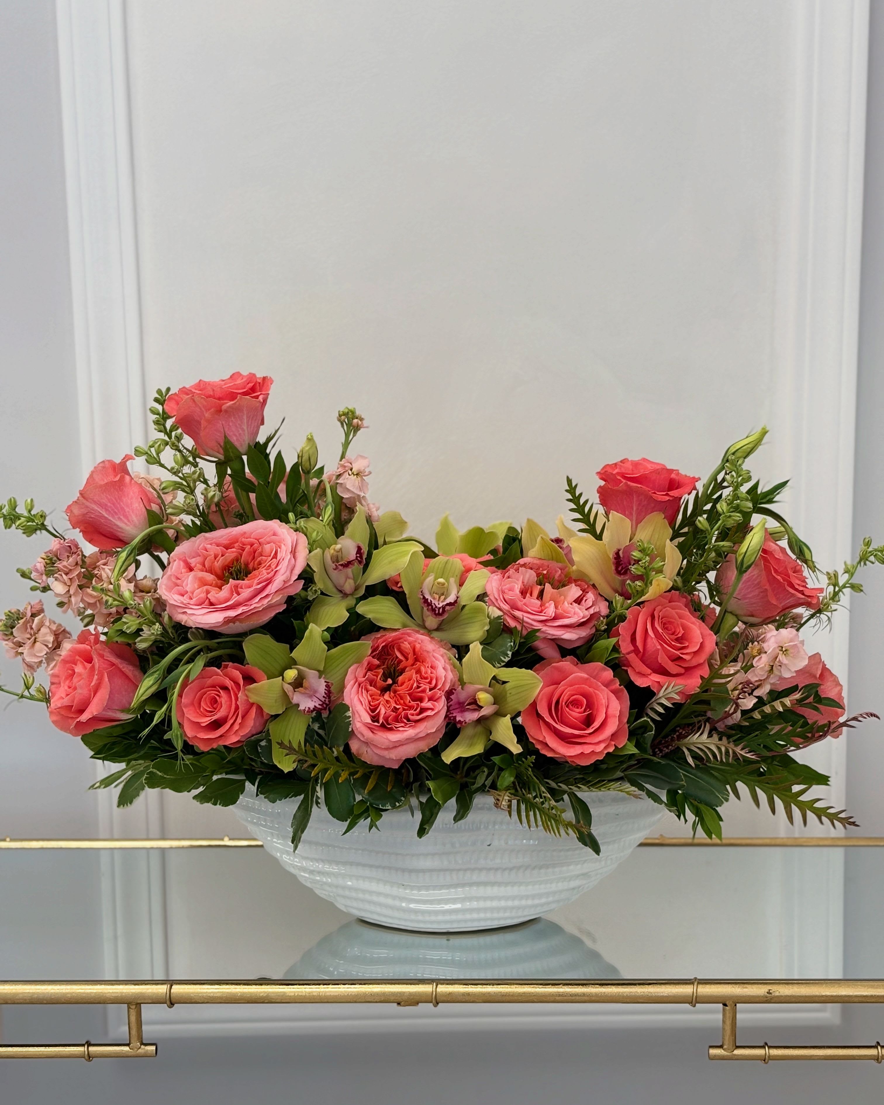 Coral Breeze By VLM Flowers - The arrangement has a wonderful combination of coral roses and green cymbidium orchids, which resembles a coral breeze. In the photo, you see the deluxe size.