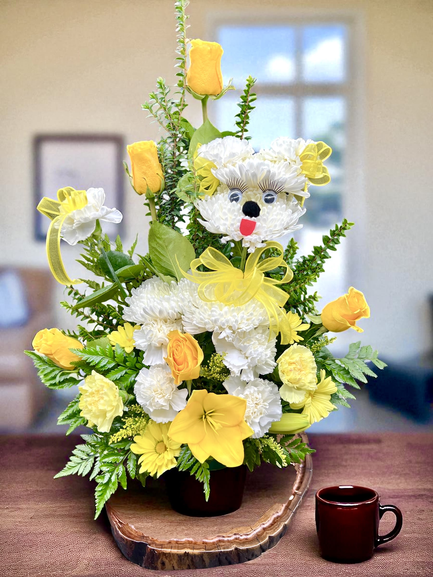 Dog 1 - Brighten someone’s day with this playful and cheerful floral design shaped like a cute little puppy! Crafted with fresh white carnations to form the puppy’s face, complete with big eyes, a sweet black nose, and a playful red tongue. Surrounded by sunny yellow roses, lilies, and vibrant greenery, this arrangement is full of joy and warmth. Perfect for birthdays, get-well wishes, or simply sending a smile!  CAN BE MADE ON ANY COLOR! JUST REQUEST IT PLEASE.