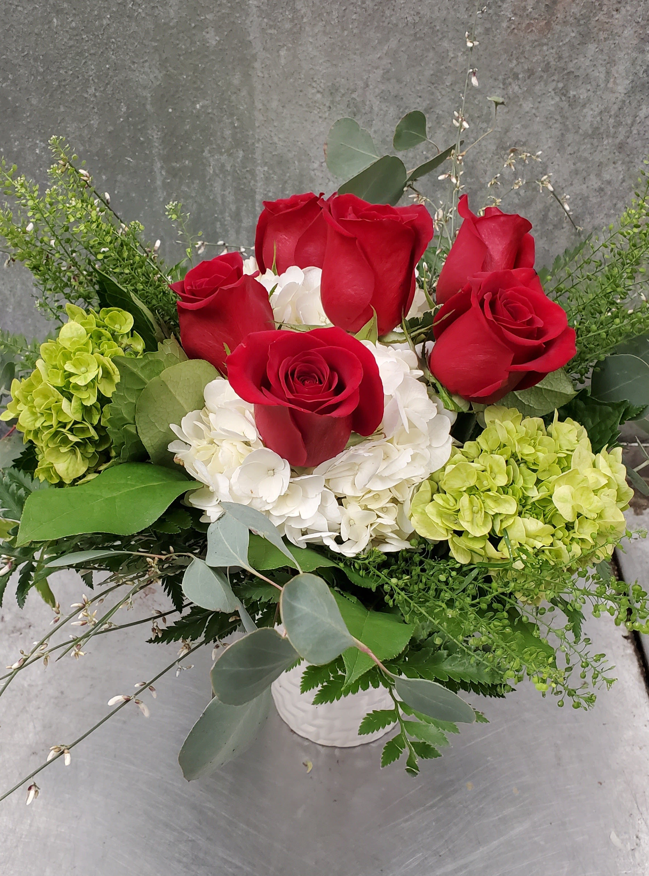 You Make Me Happy  You Make Me Happy  -  You Make Me Happy Modern. Romantic. Thoughtfully Styled.  Say it from the heart with You Make Me Happy — a low, stylized arrangement that blends elegance with artistic flair. This chic design features:  Lush hydrangea for softness and volume  Elegant roses to express love and admiration  A mix of seasonal greens for texture and contrast  Beautifully arranged in a compact, modern style, this floral design is perfect for your love— or anyone who makes your heart smile.