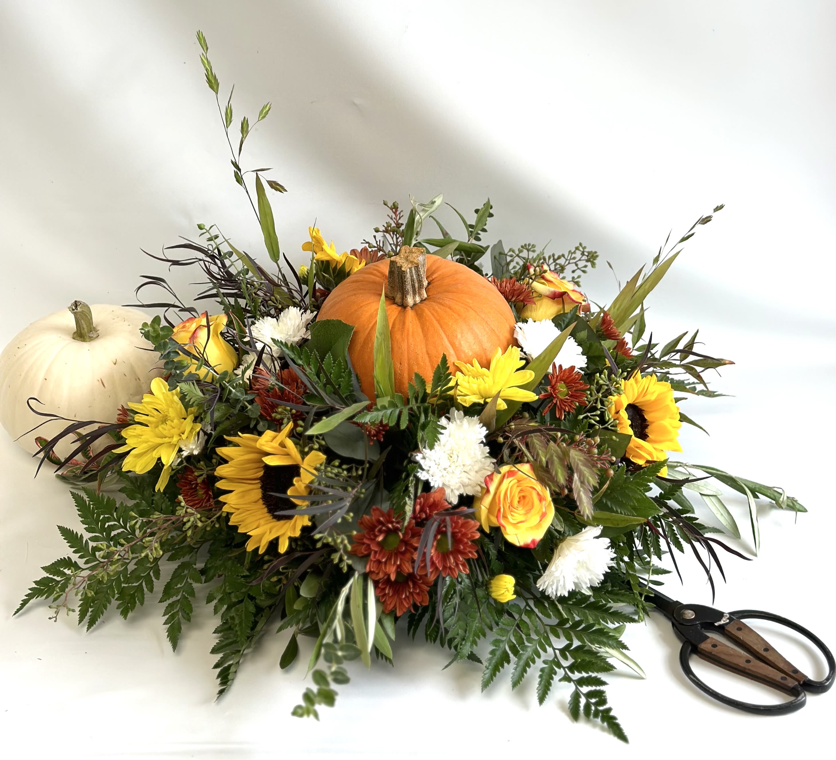Thanksgiving Pumpkin Centerpiece - A seasonal centerpiece, perfect for the holiday. Includes a fresh pumpkin in the middle. Lots of nice foliage and florals. 