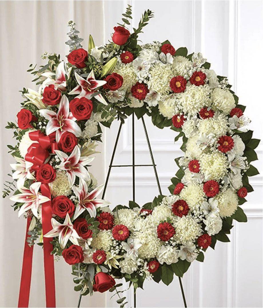 Red &amp; White Circle Funeral Wreath - This Standing Red and White Funeral Wreath is a beautiful reflection of your love and sympathy. Red and white flowers such as roses, football mums, carnations and more are accented by baby's breath and salal. Sent directly to the funeral home by family, friends and business associates, DGM Flowers use only the freshest flowers available so colors and assortment may vary. The Premium measures approximately 34&quot;H x 34&quot;W without easel and Standard measures approximately 30&quot;H x 30&quot;W without easel.  Includes:&nbsp; • White Mums&nbsp; • White Carnations&nbsp; • White Alstroemeria&nbsp; • Stargazer Lilies&nbsp; • Red Roses&nbsp; • Red Asters&nbsp; • Baby's Breath  
