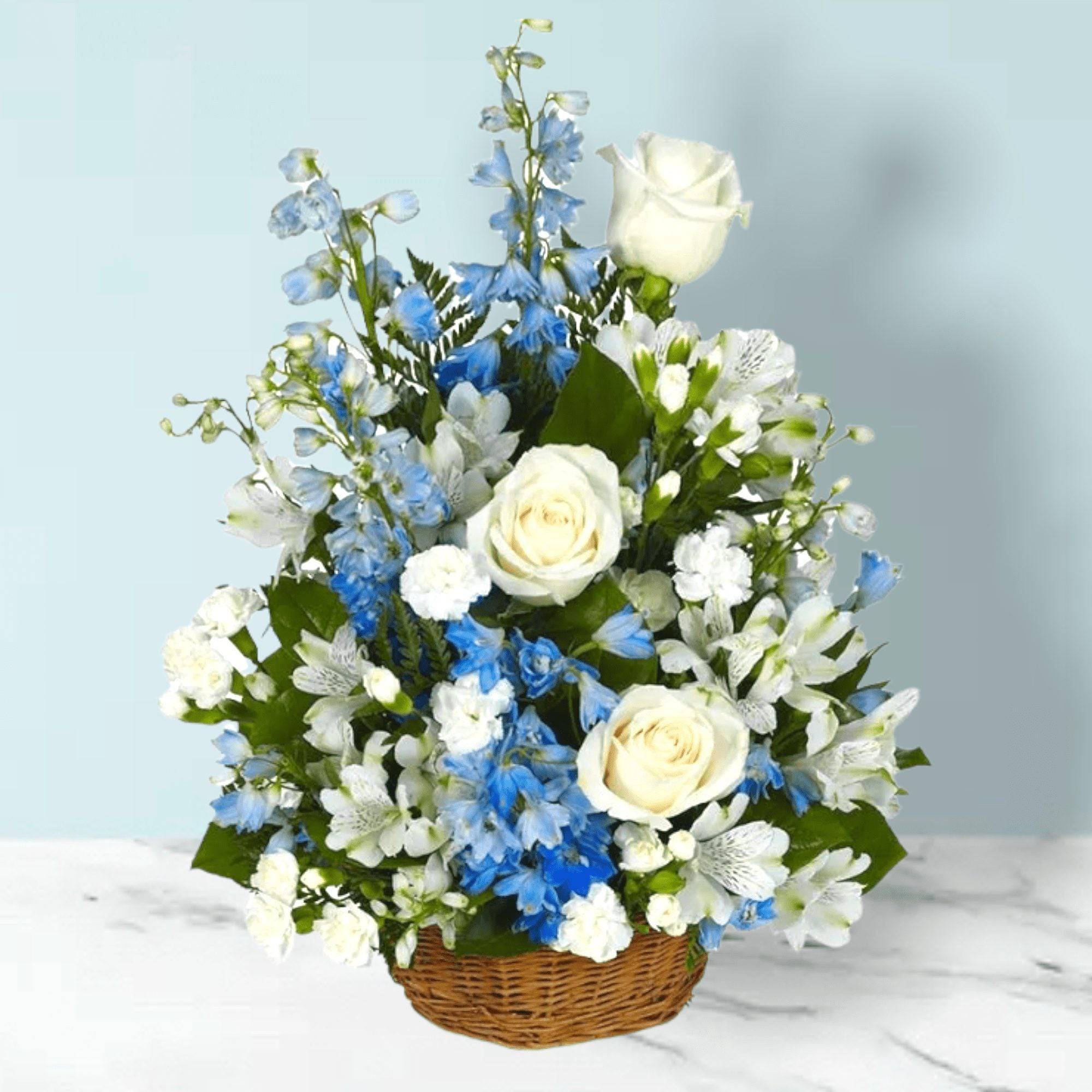 Peaceful Wishes Flower Basket - Our Peaceful Wishes Basket is sure to bring comfort to its recipient. Tranquility is the word that immediately comes to the forefront in describing this serene yet exceptional floral creation of blue delphinium, white roses, white mini carnations and white alstroemeria in a willow basket. this sympathy flower basket is perfect for expressing condolences and offering comfort during difficult times.  &nbsp;Measures 18&quot;H by 14&quot;L. - BF211-11K