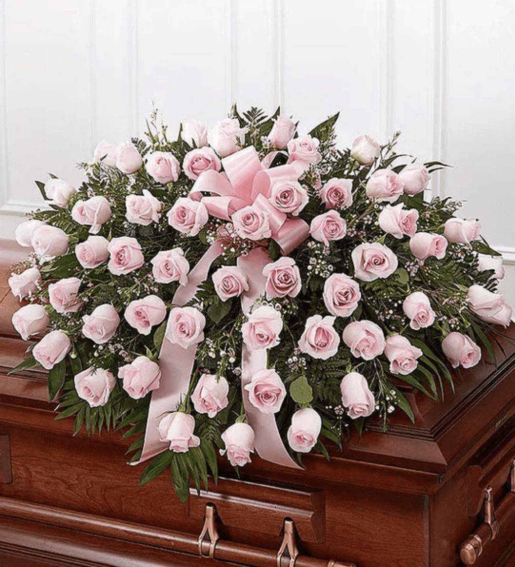 Pink Rose Half Casket Cover - The Pink Rose Half Casket Cover by DGM Flowers | Fort Lauderdale Florist is a stunning tribute to a loved one. The ultimate symbol of grace, love and admiration, soft pink roses are a sentimental way to honor someone who was deeply cherished. The Pink Rose Casket Arrangement is a half casket cover, crafted with care and artistry by DGM Flowers with over 50 of these soft-hued blooms and accented with a pink satin ribbon, is an unforgettable way to commemorate a lifetime of unconditional love.&nbsp; &nbsp;  Half casket cover arrangement of pink roses, waxflower and fresh greenery; accented with a pink satin ribbon Arrangement measures approximately 16&quot;H x 36&quot;L x 28&quot;D Traditionally sent by the immediate family to the funeral home We use only the freshest flowers available, so colors and varieties may vary