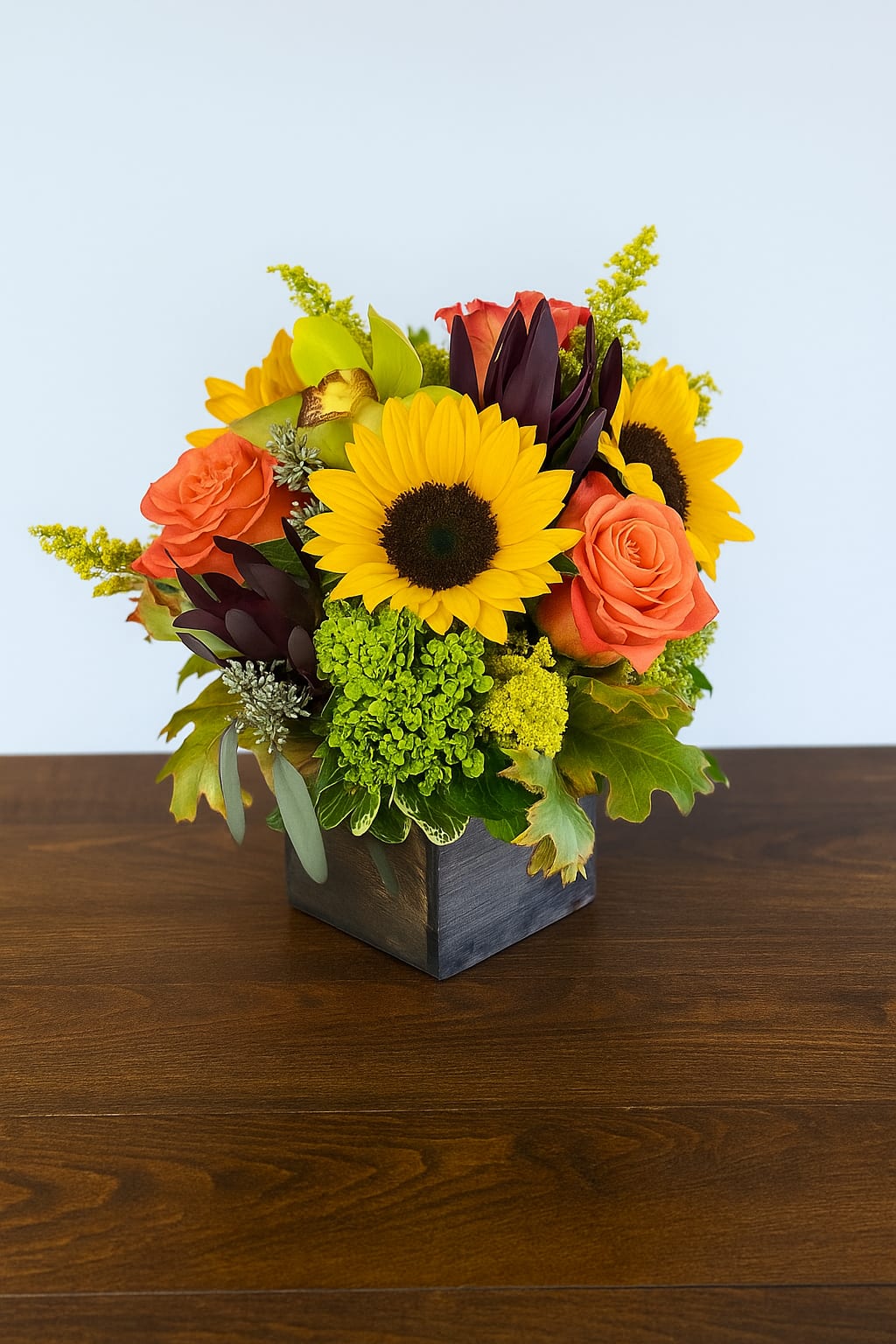 Harvest Bloom Box Harvest Bloom Box - Celebrate the beauty of fall with our Harvest Bloom Box, a stunning arrangement handcrafted by Polk Street Florist in San Francisco. Bright sunflowers, warm orange roses, and rich seasonal greens come together in a rustic wooden box — the perfect blend of cheerful and cozy. Ideal for autumn birthdays, Thanksgiving gatherings, or simply adding a touch of seasonal charm to your home. Flower varieties and colors may vary based on seasonal availability.