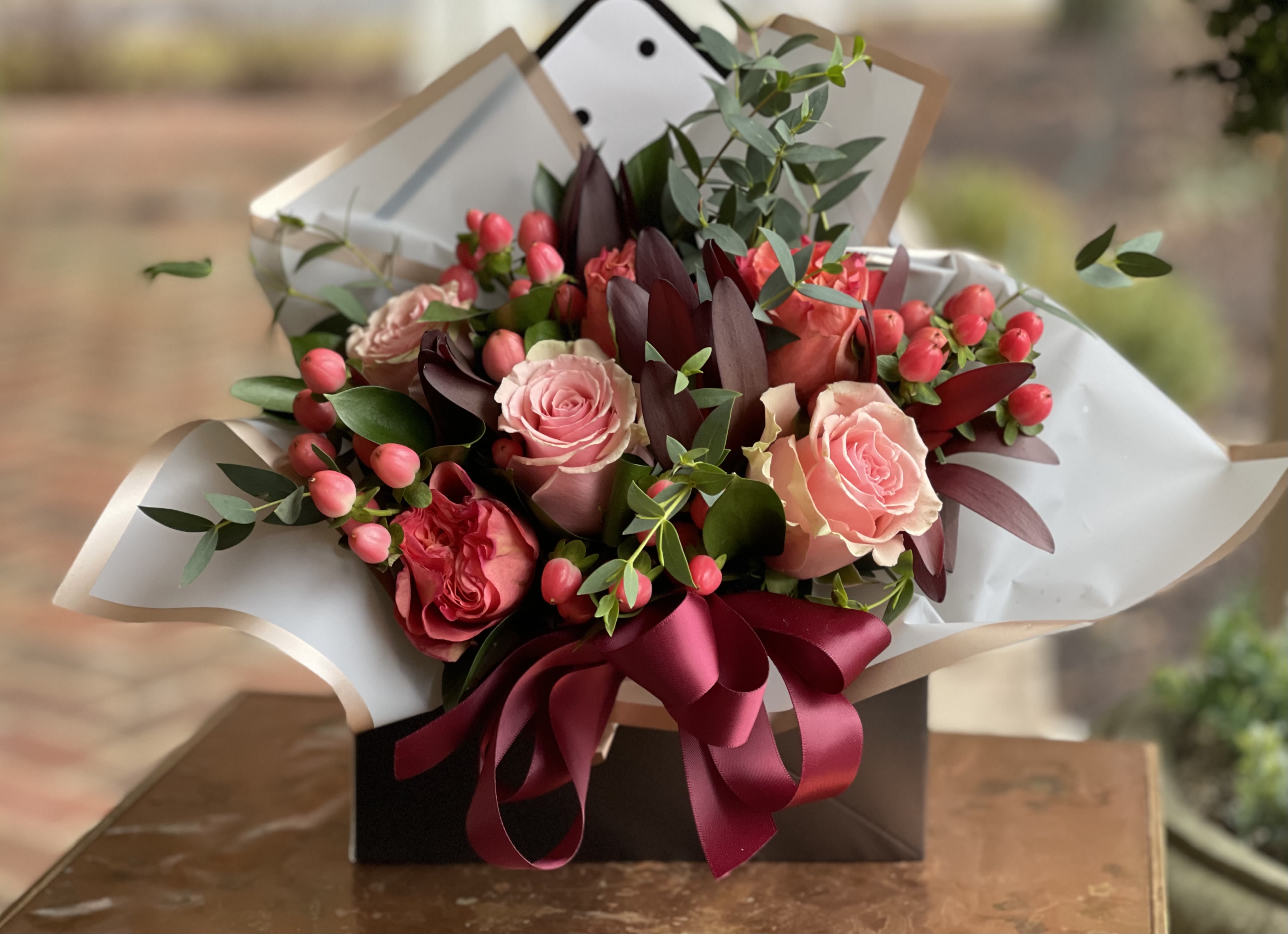 Love Note - Love Note – Romantic Floral Arrangement by Petals in Wilmington, Delaware   Send a message straight from the heart with Love Note, a charming and creative floral design handcrafted by Petals, your trusted local florist in Wilmington, Delaware. This romantic arrangement features a delightful mix of pink roses, orange roses, and coral hypericum berries, accented with fresh seasonal greens — all artfully presented in a stylish envelope container finished with fancy floral paper for a one-of-a-kind touch. Perfect for anniversaries, birthdays, Valentine’s Day, or simply to say “I love you,” the Love Note arrangement captures warmth, color, and heartfelt emotion in every bloom. Each piece is designed with care by our expert Wilmington florists and available for same-day delivery throughout the area.  We offer same day tax free delivery to Wilmington, Newark, Kennett Square, Hockessin and surrounding areas.