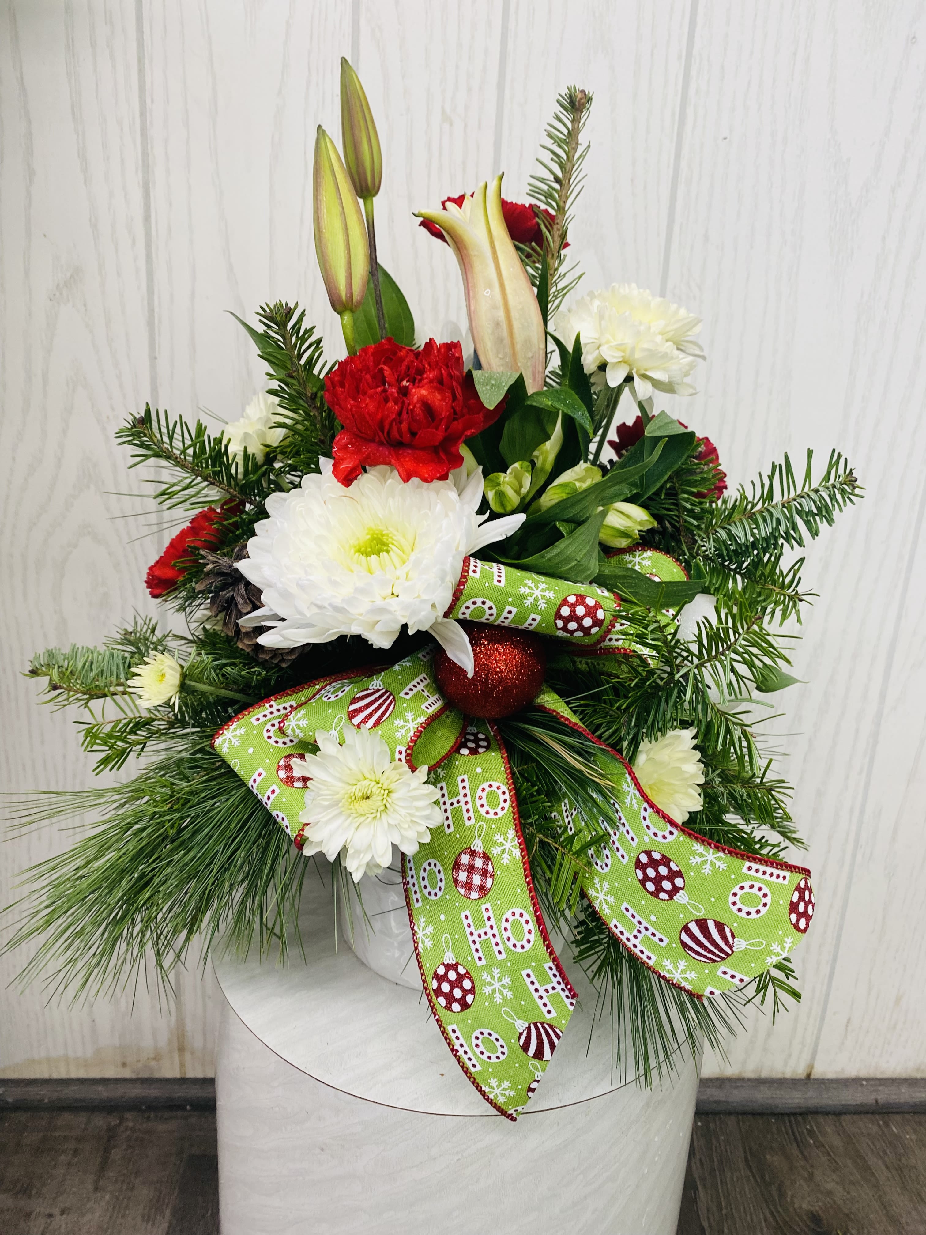 O Tannenbaum Holiday Arrangement - This festive holiday arrangement includes traditional holiday colors arranged in a tree-imprinted white ceramic container. Approximately 13 inches tall. Deluxe &amp; premium include roses. Flower substitution may be necessary based on current floral inventory. The overall look, feel and value will be maintained. 