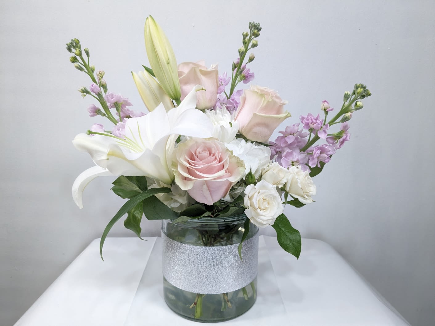 Soft Touch - This arrangement contains white gerbera daisies, soft color of roses, light lavender stock, and other seasonal blooms. APPROXIMATE DIMENSIONS: 15&quot; D x 13&quot; H 
