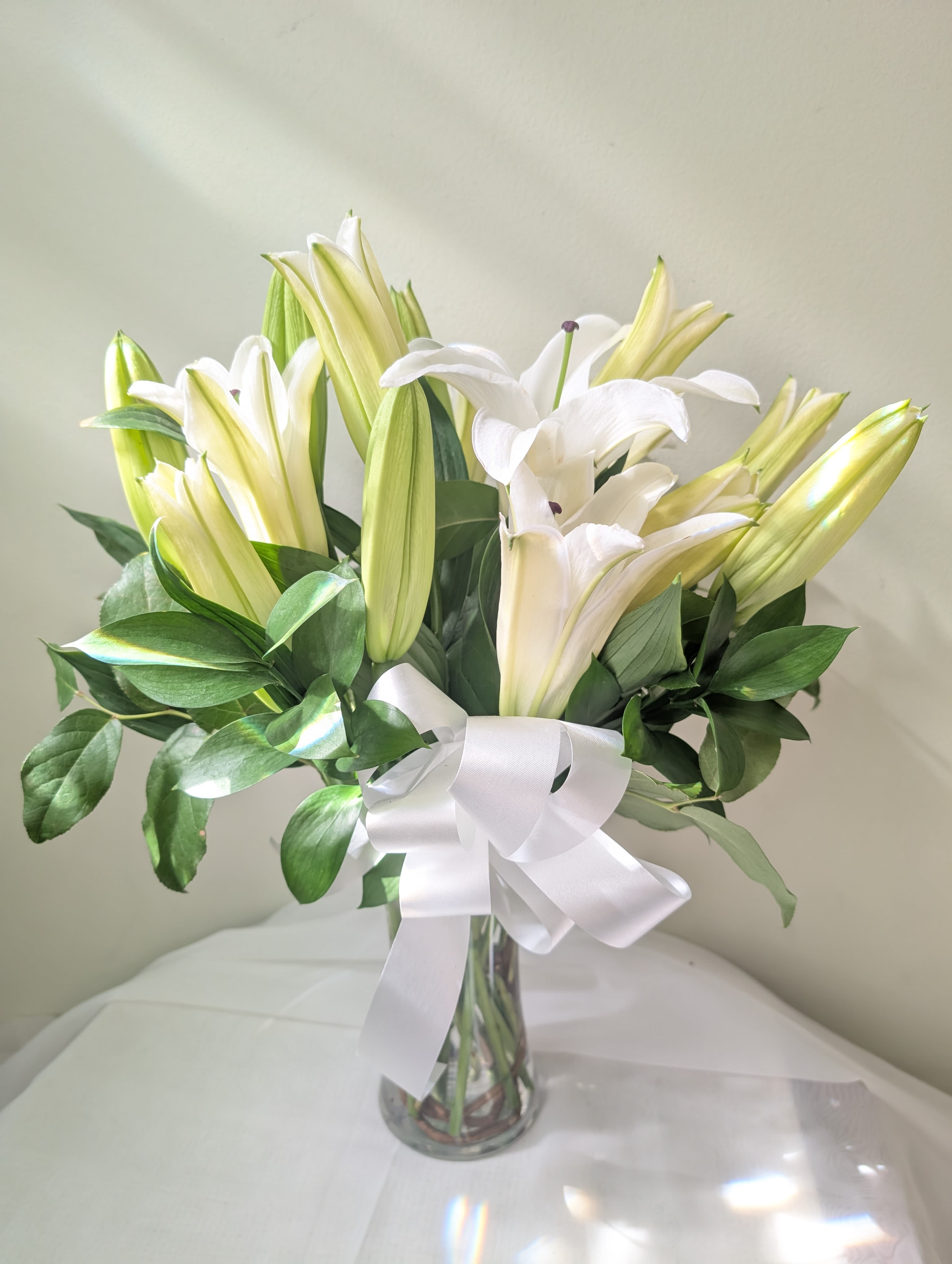 Peaceful Evening - White lilies stand tall and beautiful. Send an impactful gift to somebody whether it be for saying I am sorry or celebrating the new year. This arrangement instantly elevates any room and fills the space with that distinct sweet-smelling lily perfume.  1st Image: Standard 2nd Image: Premium