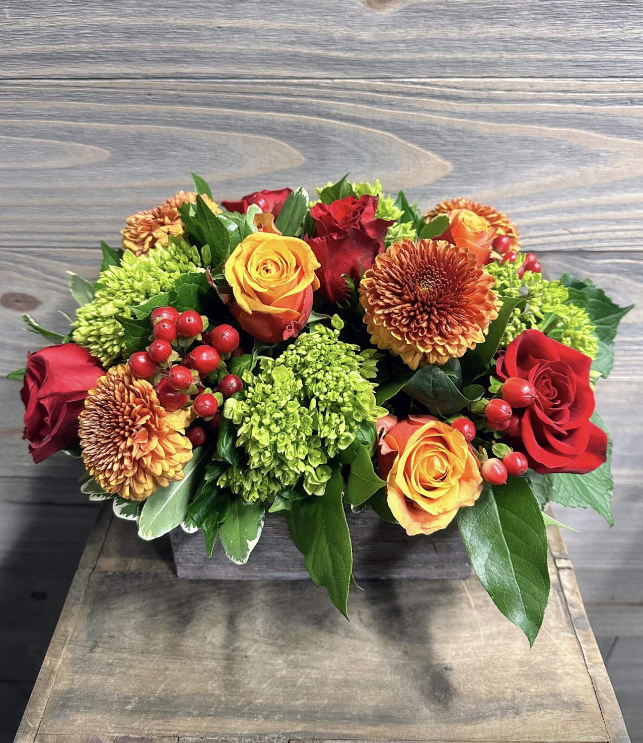 Maple - A beautiful floral piece perfect for the center of a table in a specialty long and low wooden box with bright roses, hydrangeas, and mums.
