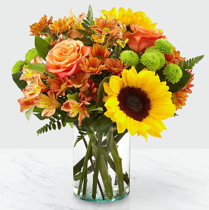 Autumn Splendor Bouquet - Say hello to autumn with this bouquet filled with bold harvest hues and luscious blooms. Thoughtfully arranged with the freshness of fall in mind, a collection of orange roses, bright sunflowers and orange alstroemeria is set beautifully in a clear glass vase. Whether it's seasonal décor for your home or a gift for a loved one, our Autumn Splendor Bouquet is sure to make any home its placed in feel warm and bright. Bouquet sizes are approximate.  14&quot;H x 14&quot;W