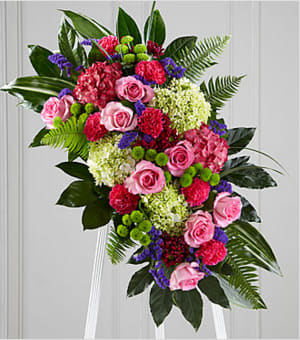 The FTD Refreshing Mix Standing Spray - This glorious celebration of life combines the vibrant, hopeful colors of spring in a standing arrangement designed to inspire happy memories of times gone by. Handcrafted by a local FTD artisan florist of bright and beautiful blossoms that include pink roses, magenta carnations, purple statice and hydrangeas, green button pompons and hydrangeas and daisy pompons all arranged against a background of lush green aralia and aspidistra leaves. It is designed for display on an easel making an impressive, memorable expression of sympathy at a wake, funeral or graveside service.  Your purchase includes a complimentary personalized gift message.