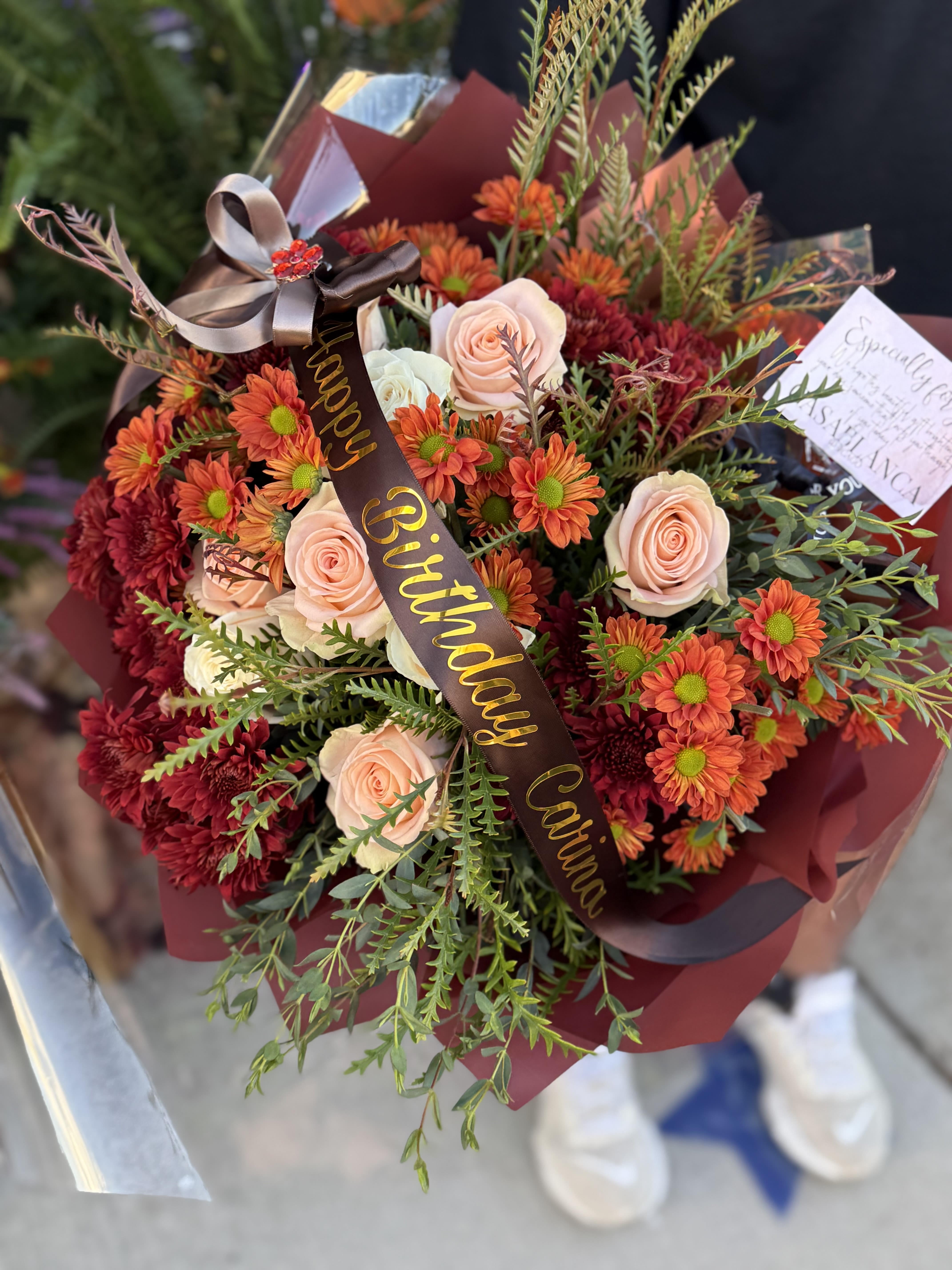 Fall Birthday Bouquet  - Peach and white roses with golden burnt orange and orange mums. Fall foliage and our maroon korean wrapping paper with a custom ribbon message. 