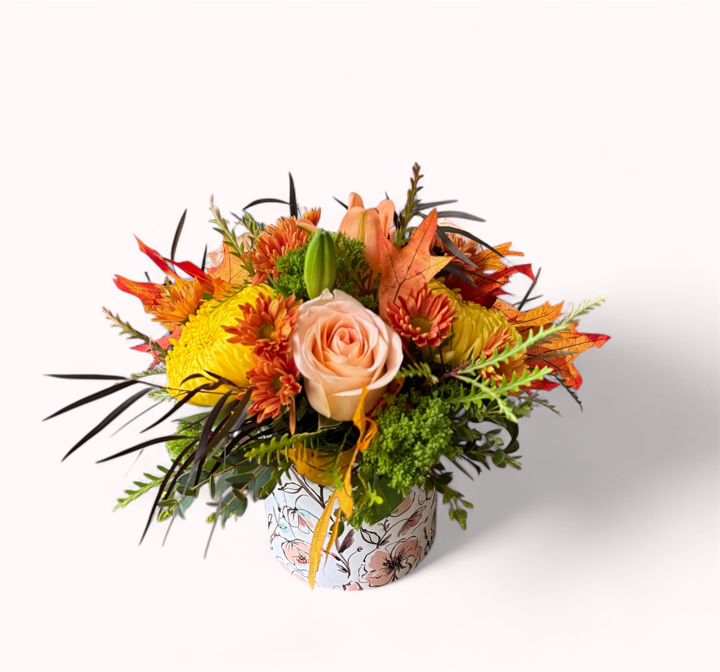 Autumn Glow - Bring the warmth of fall indoors with Autumn Glow. Featuring soft peach roses, golden mums, and orange accents surrounded by rich greenery, this cheerful bouquet  adds a cozy seasonal touch to any space.