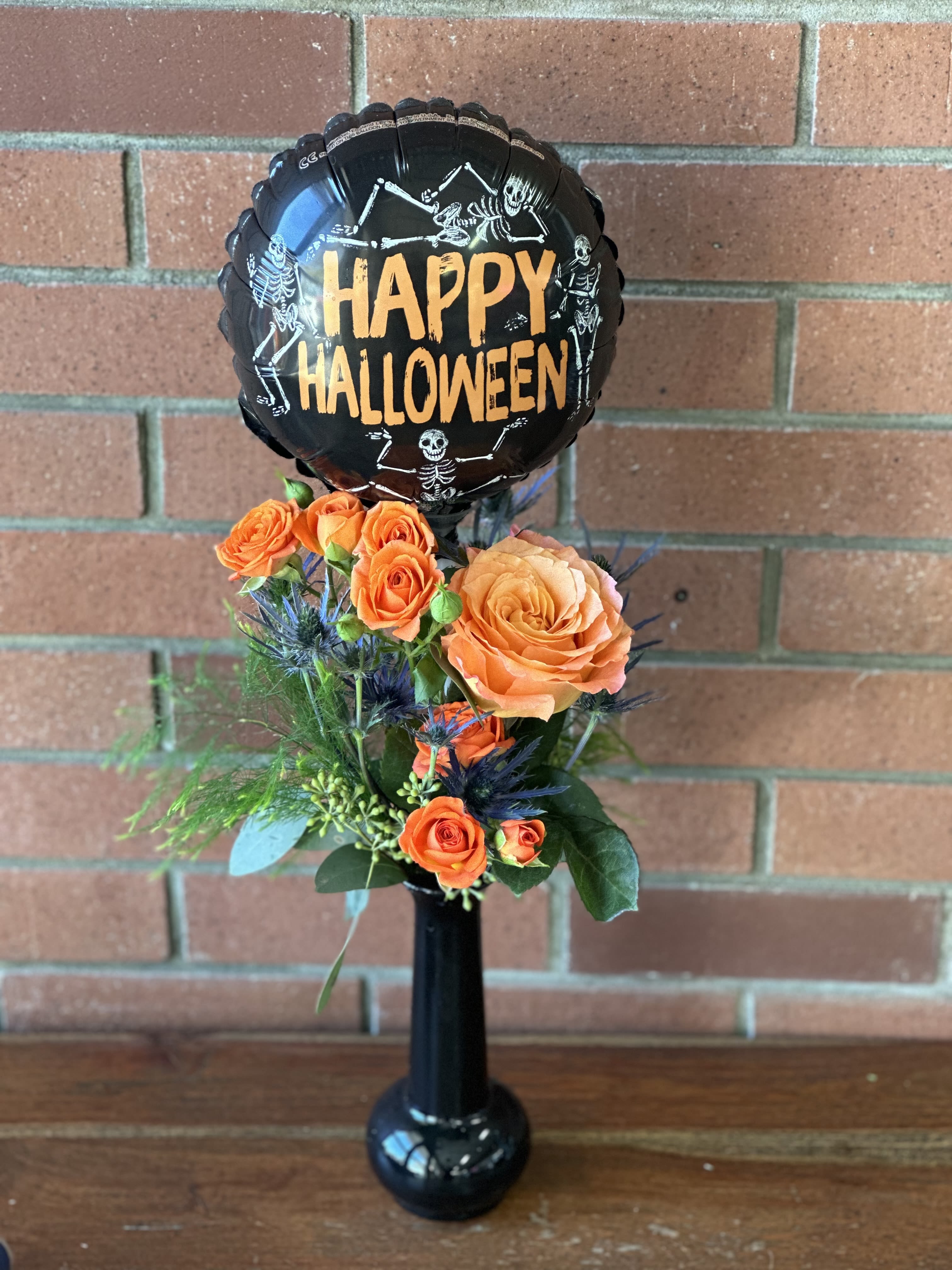 Happy Halloween Bud-vase & Balloon Happy Halloween Bud-vase & Balloon - Black acrylic bud vase filled with blue/ purple thistle and orange roses and spray roses accented with eucalyptus and greenery - delivered with a Happy Halloween balloon