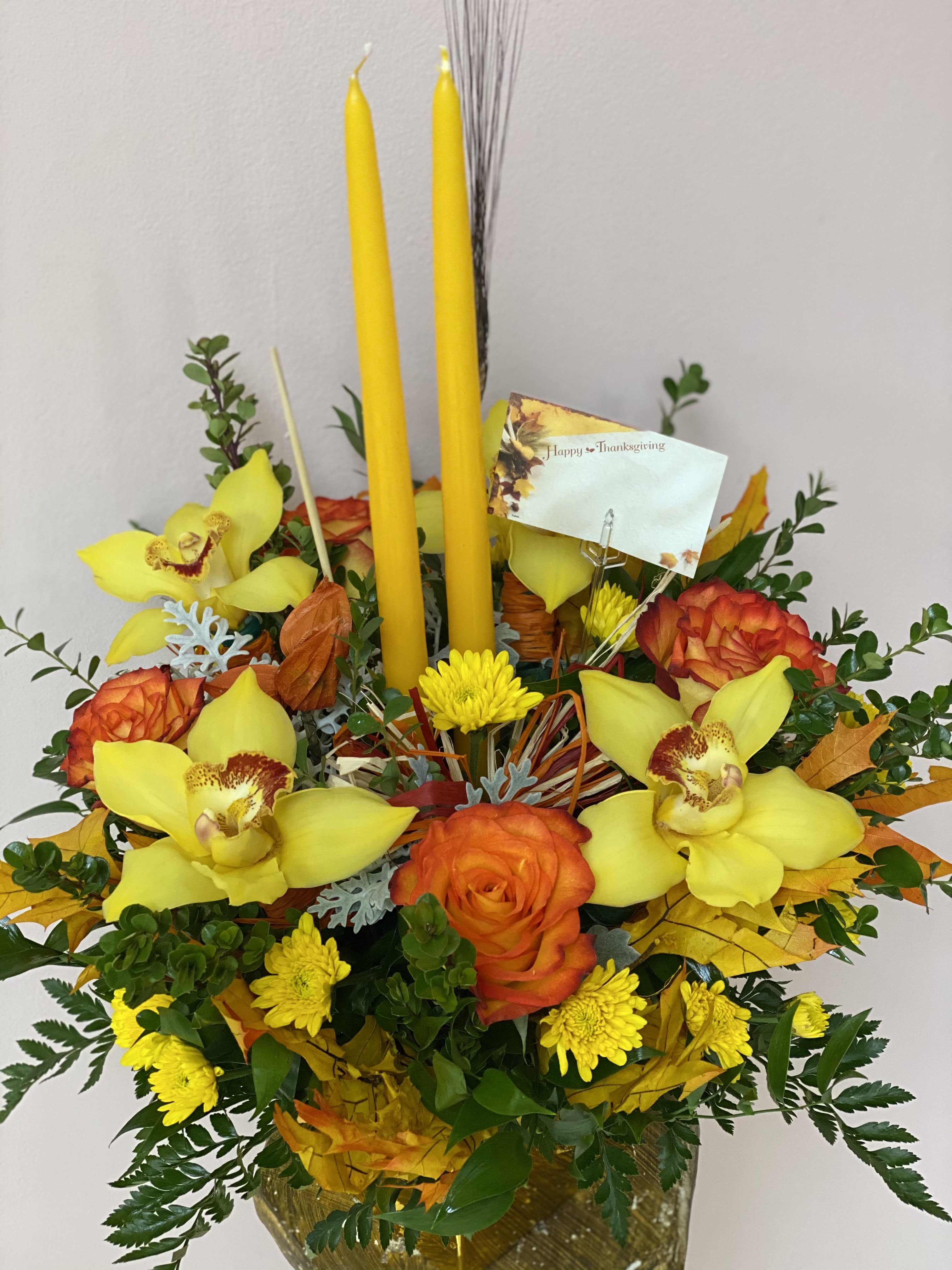 TG 6 - Thanksgiving centerpiece featuring an assortment of fall flowers arranged in a floral foam container.  * Candle color and florals may vary based on availability.