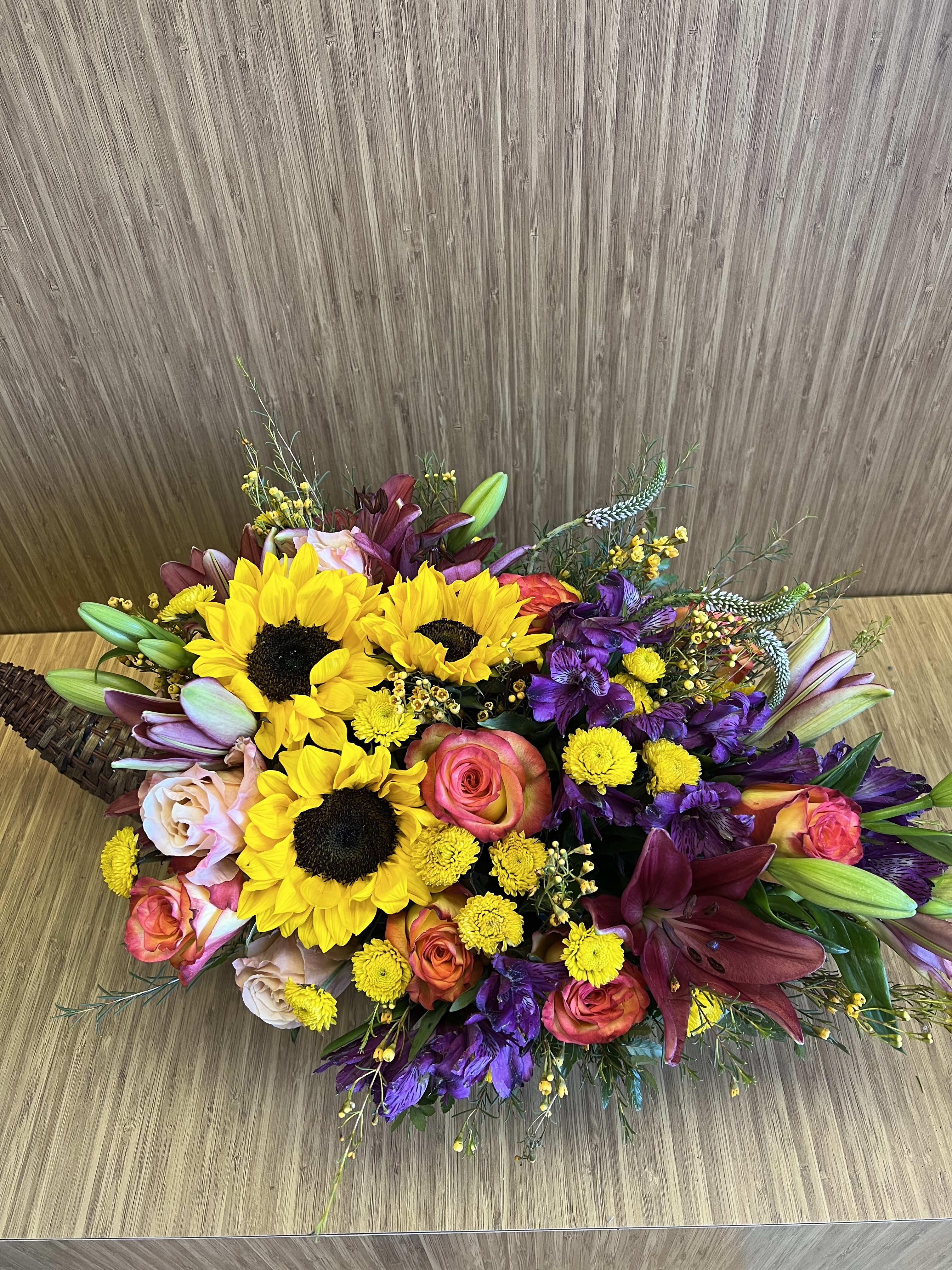 TG 7 - Thanksgiving centerpiece featuring an assortment of fall flowers arranged in a cornucopia.  * Candle color and florals may vary based on availability.
