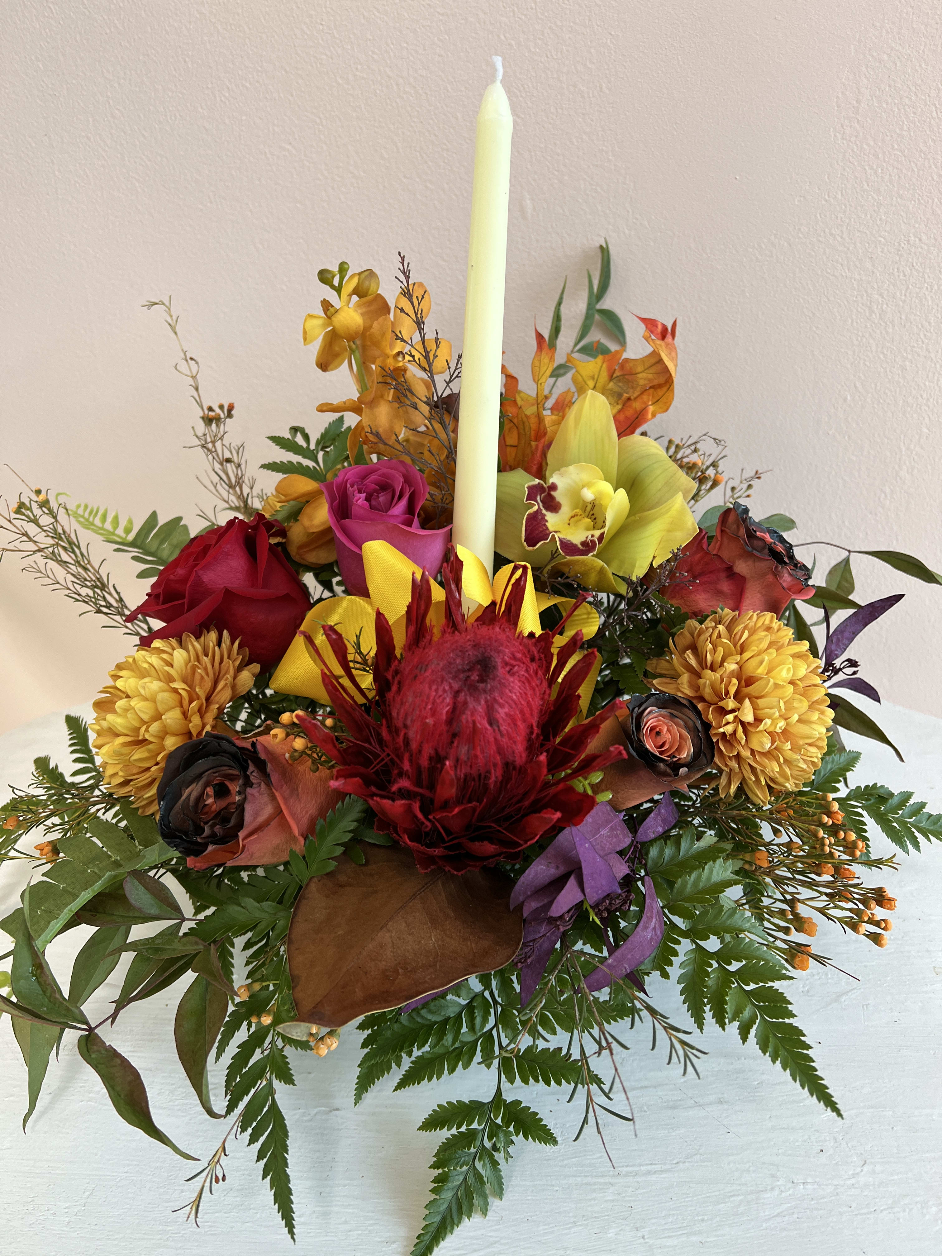 TG 8 - Thanksgiving centerpiece featuring an assortment of fall flowers arranged in a floral foam container.  * Candle color and florals may vary based on availability.