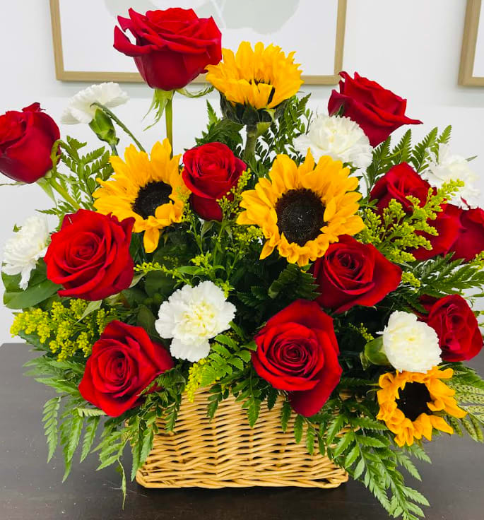 Fields of Sunshine - A sunny sunflower bouquet gets an autumnal spin with  rich red roses. The cheerful autumn floral arrangement is rich with color, making it a stylish, energizing pick for any occasion.  (Deluxe pictured) 
