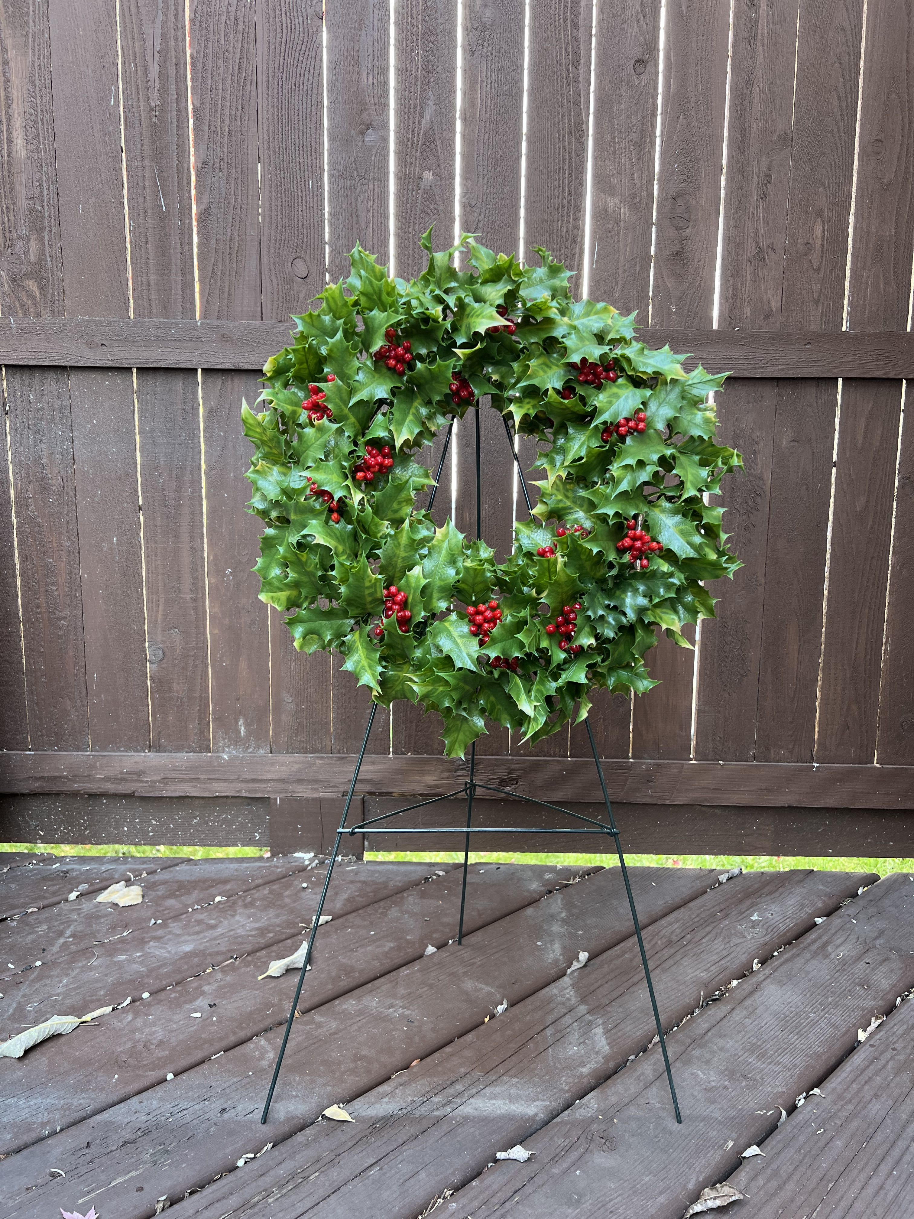Grave Wreath - Decorate and remember a loved one's grave with this reusable, plastic wreath and stand combination. Decorated with greenery and berries. Attached to a 30&quot; easel. Just remember to remove from the grave 1 week after the Holidays and before cemetery clean up begins. Folds flat for storage. Standard design comes as shown. Deluxe adds in a few ornaments and ribbon. If interested in a premium design, call for pricing and we will add in ornaments, ribbon and silk flowers for an additional fee. Delivery available(fees applied): if the grave is marked and locatable. Call to inquire.
