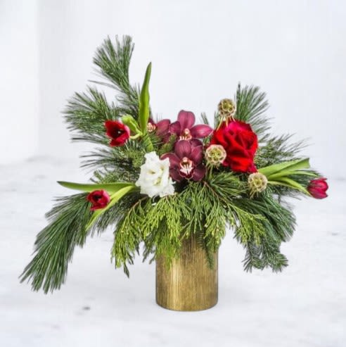 Winter Enchantment Bouquet - Embrace the magic of the season with our Winter Enchantment Bouquet. This captivating arrangement combines vibrant red roses, deep burgundy orchids, festive red tulips, and delicate white blooms, nestled among lush evergreen pine and cedar branches. Perfectly arranged in a sleek gold-toned vase, this bouquet exudes elegance and warmth, making it an ideal centerpiece or holiday gift. Available for floral delivery, the Winter Enchantment Bouquet brings a touch of seasonal splendor to any space. Order now to enchant and delight your loved ones with this unique winter display!  Disclaimer: In the event the orchids shown in the photo are not available, another variety of orchids will be used to maintain the beauty and quality of the arrangement.