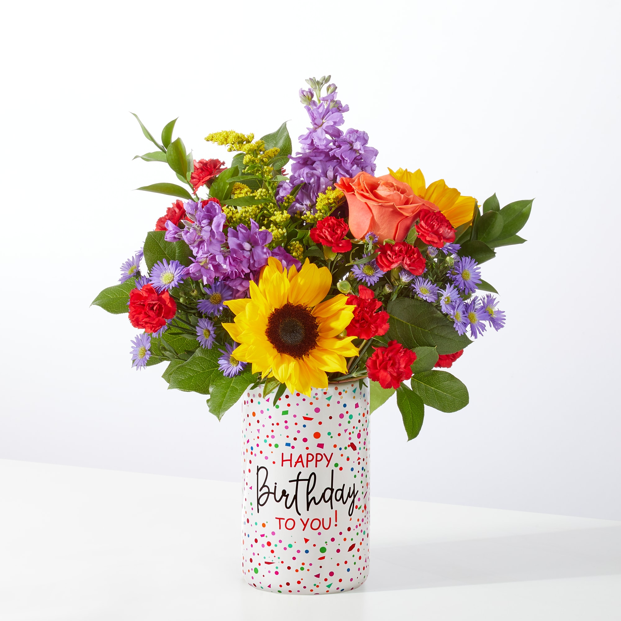 Birthday Surprise Bouquet - Bring the joy of celebration to life with our Birthday Surprise Bouquet! This vibrant arrangement bursts with sunny sunflowers, elegant roses, fragrant stock, golden solidago, charming monte casino, and lush greenery—all artfully arranged in our colorful Birthday Confetti Cylinder container.  Radiant and full of life, this bouquet is the perfect way to say “Happy Birthday!” with warmth, cheer, and style. Whether it’s for a loved one, a friend, or a coworker, the Birthday Surprise Bouquet is sure to make their day unforgettable.